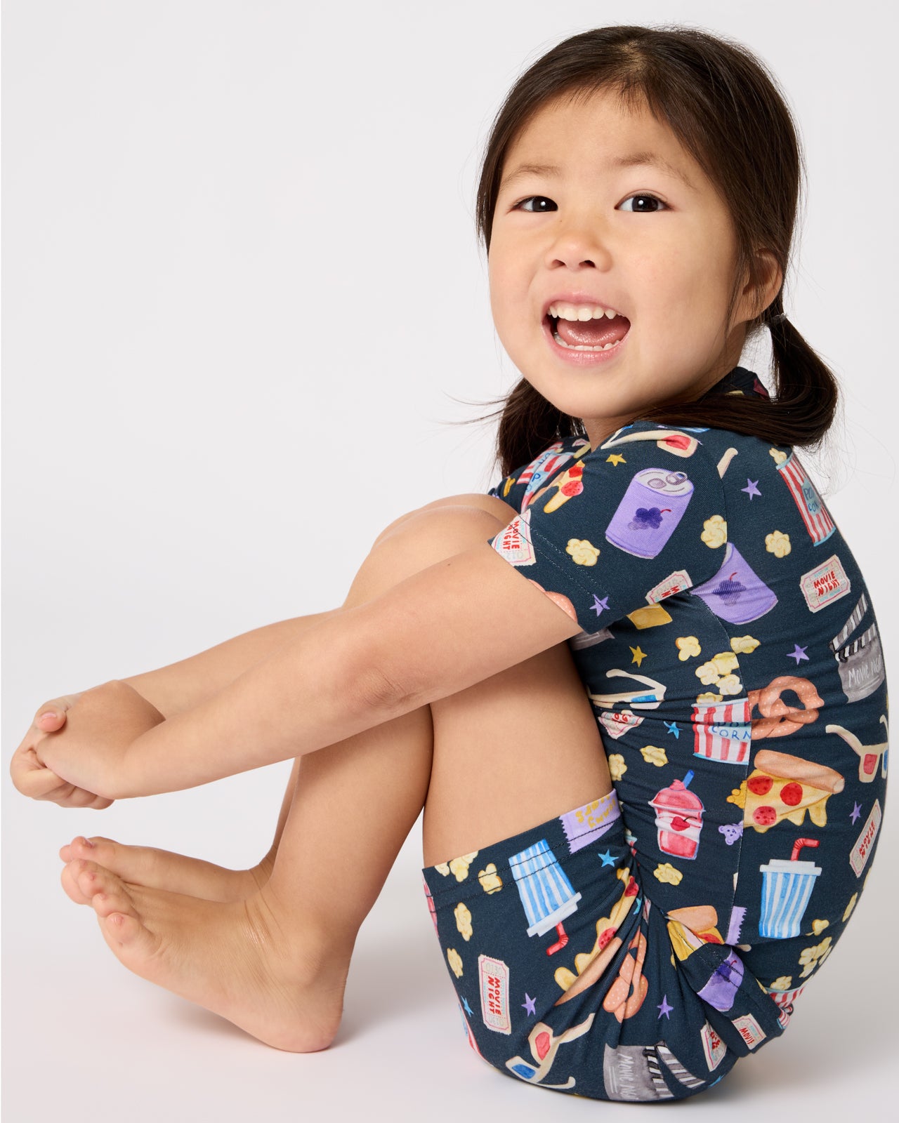 Sitting girl wearing the Movie Marathon Two-Piece Short Sleeve & Shorts Pajama Set