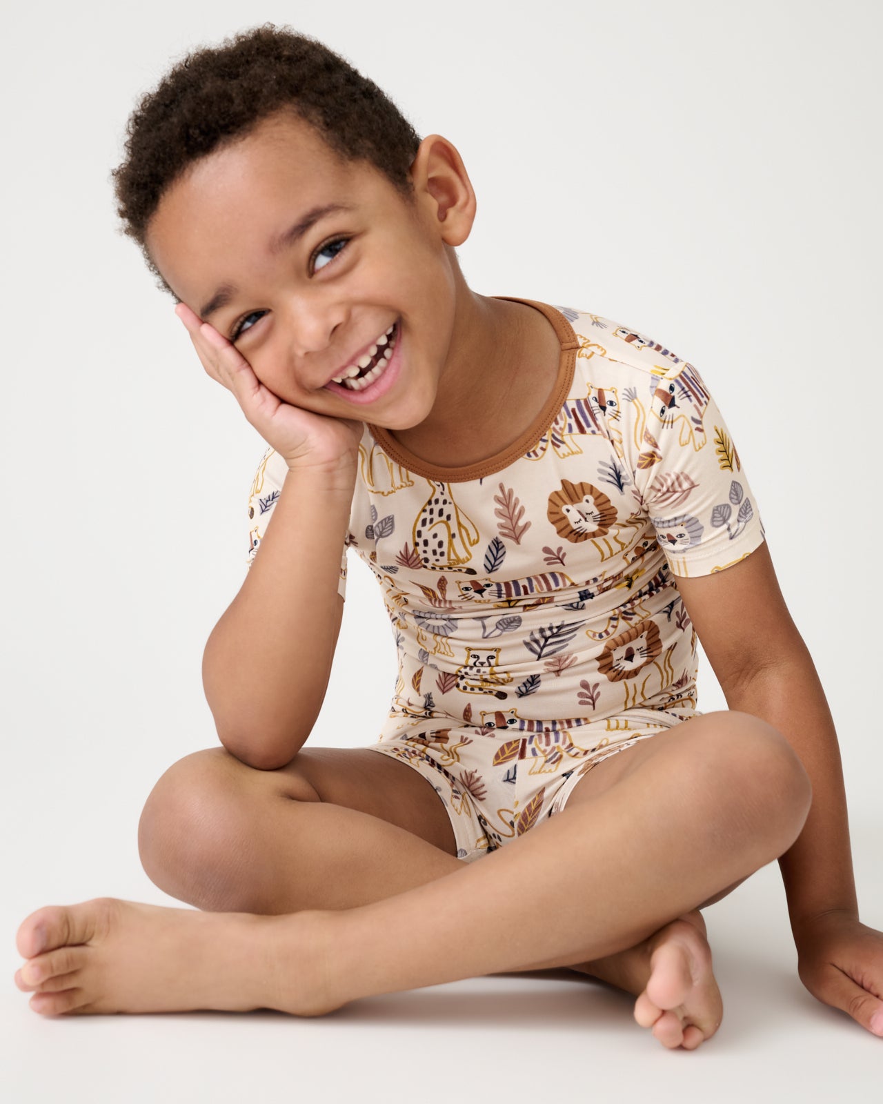 Sitting boy wearing the Savanna Friends Two-Piece Short Sleeve & Shorts Pajama Set