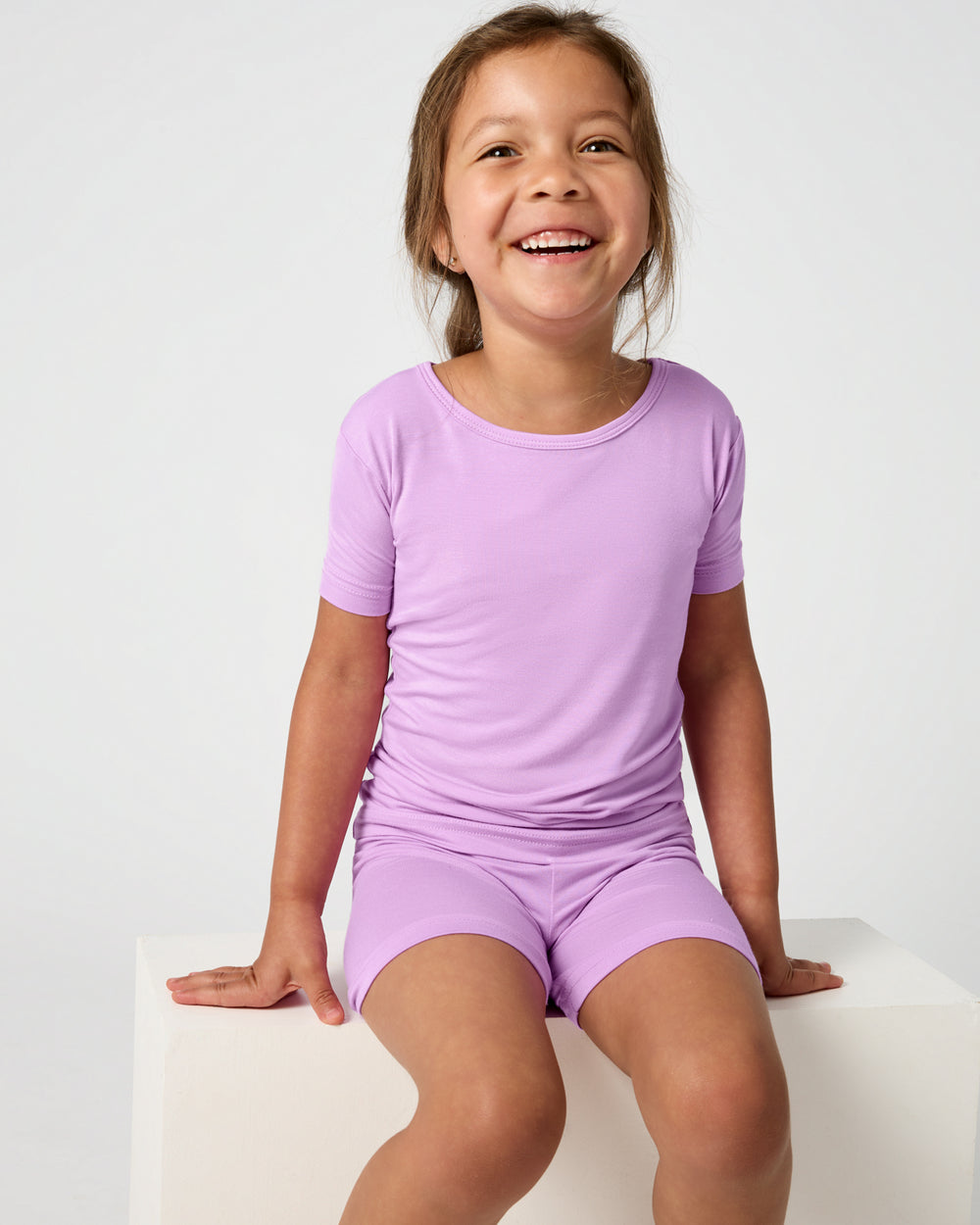 Sitting child wearing the Soft Wisteria Two-Piece Short Sleeve & Shorts Pajama Set