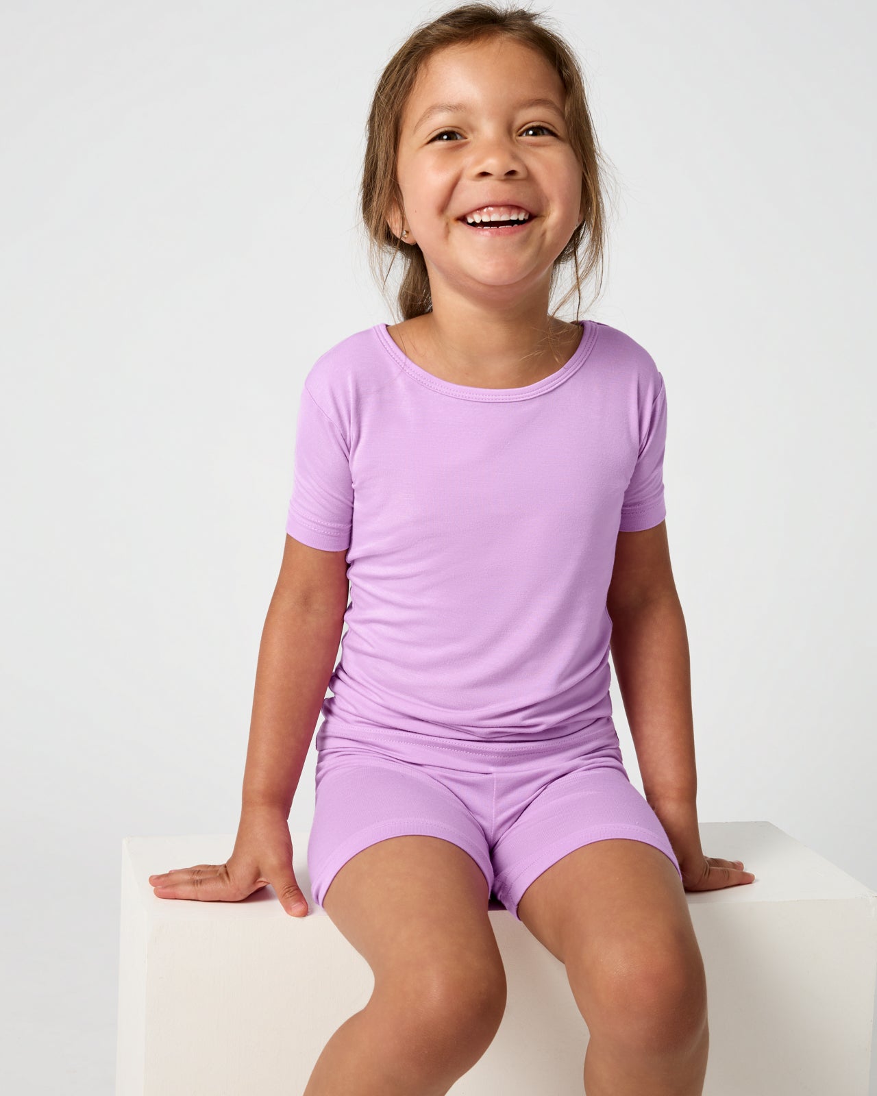 Sitting child wearing the Soft Wisteria Two-Piece Short Sleeve & Shorts Pajama Set