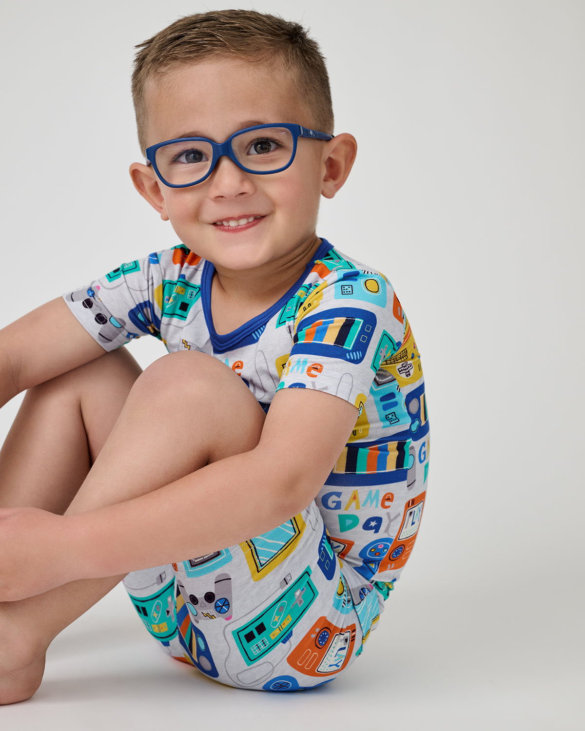 Sitting child wearing the Game On Two-Piece Short Sleeve & Shorts Pajama Set