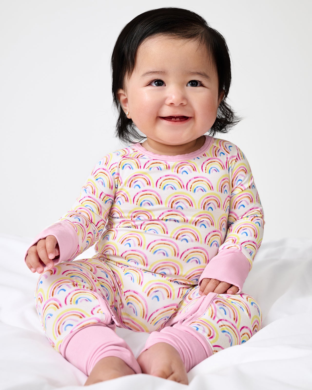 Sitting newborn wearing the Pastel Rainbows Crescent Zippy
