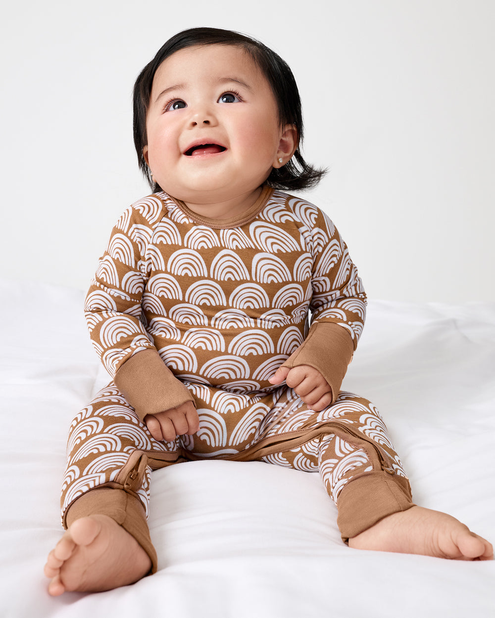 Sitting newborn wearing the Rust Rainbows Crescent Zippy