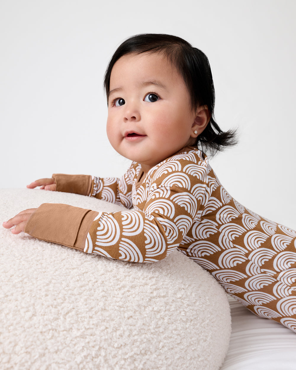 Newborn on a boucle ottoman wearing the Rust Rainbows Crescent Zippy