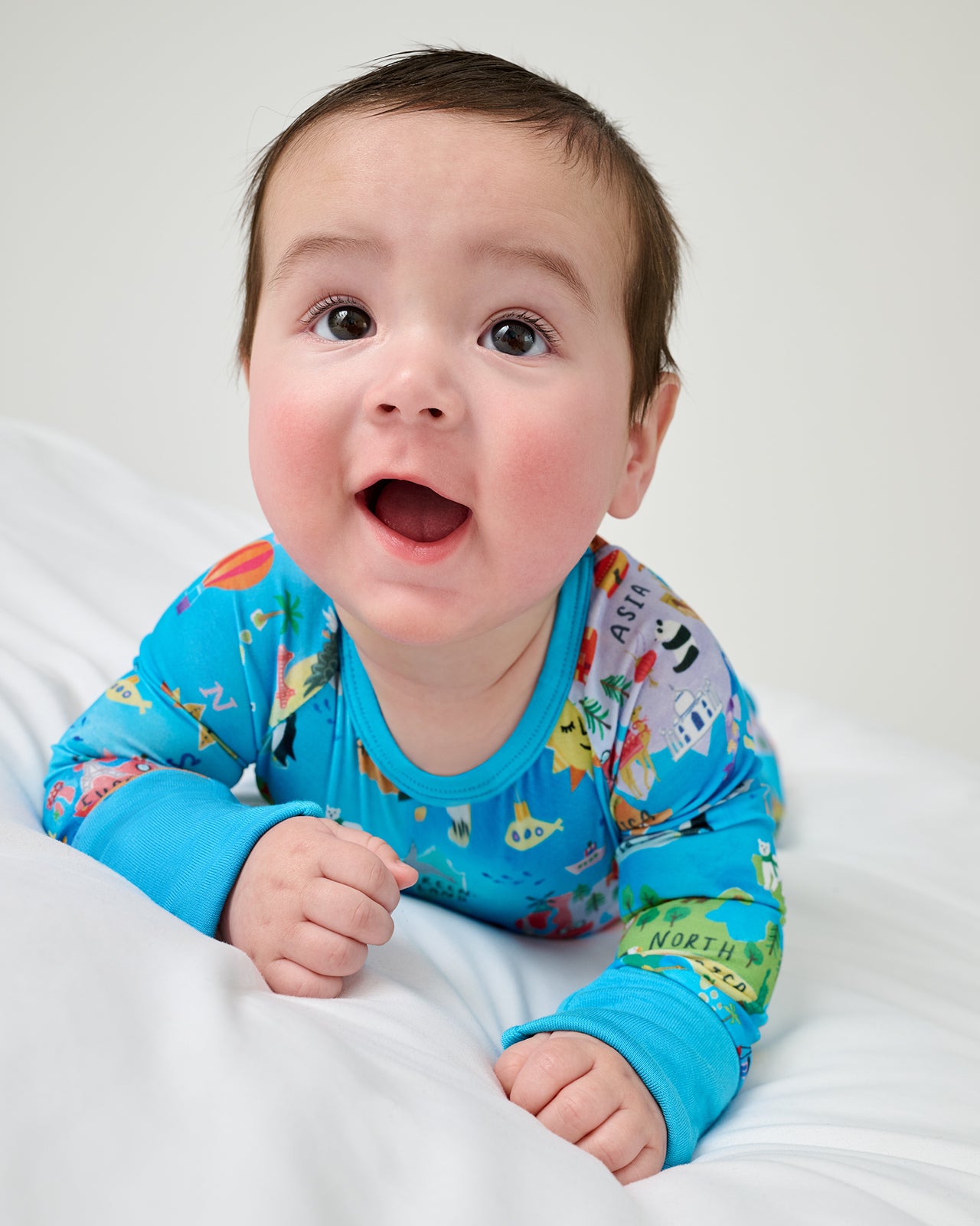 Baby on his tummy wearing the Around The World Crescent Zippy