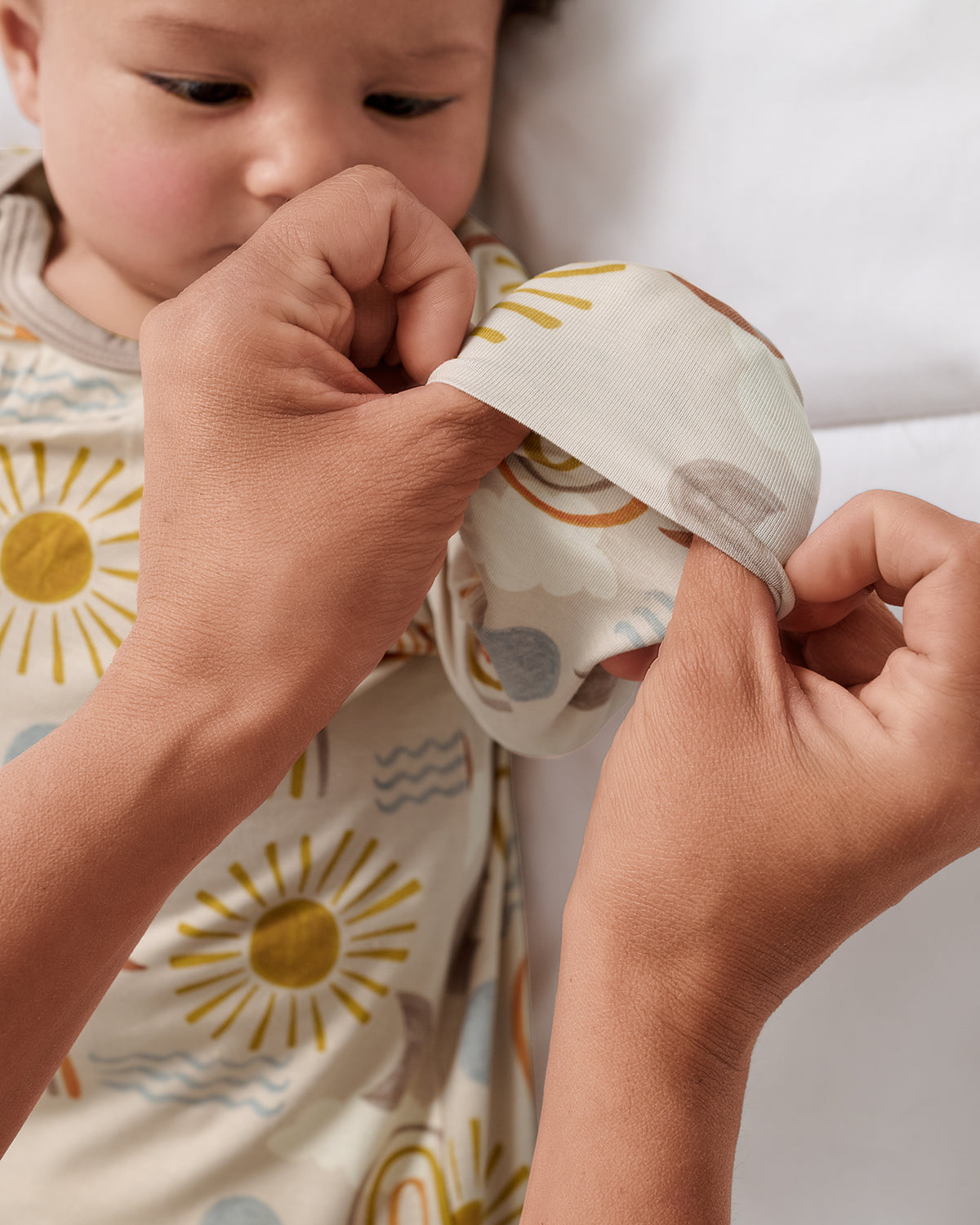 Adult demonstrating the mittens on the Desert Sunrise Infant Gown