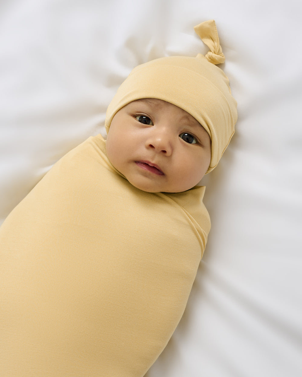 Close up of newborn wrapped in the Sunglow Swaddle & Hat Set