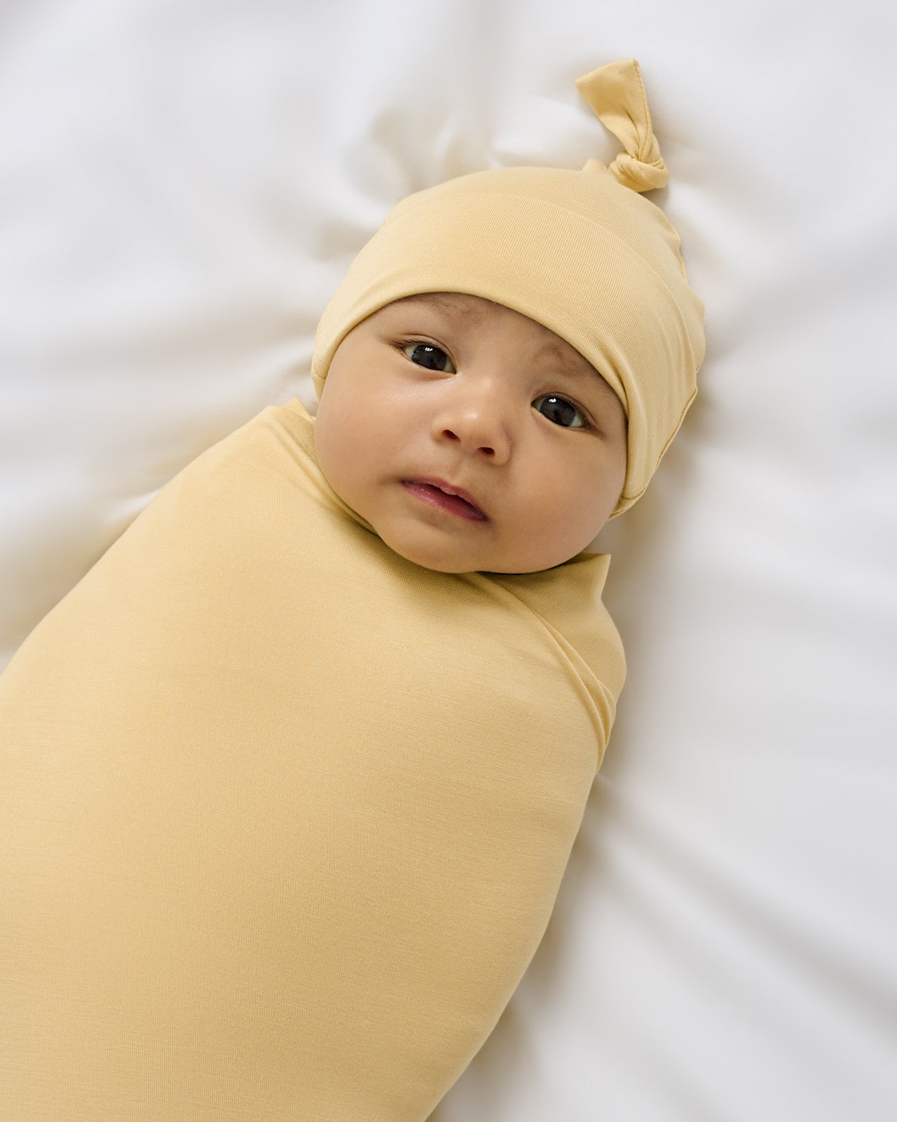 Close up of newborn wrapped in the Sunglow Swaddle & Hat Set