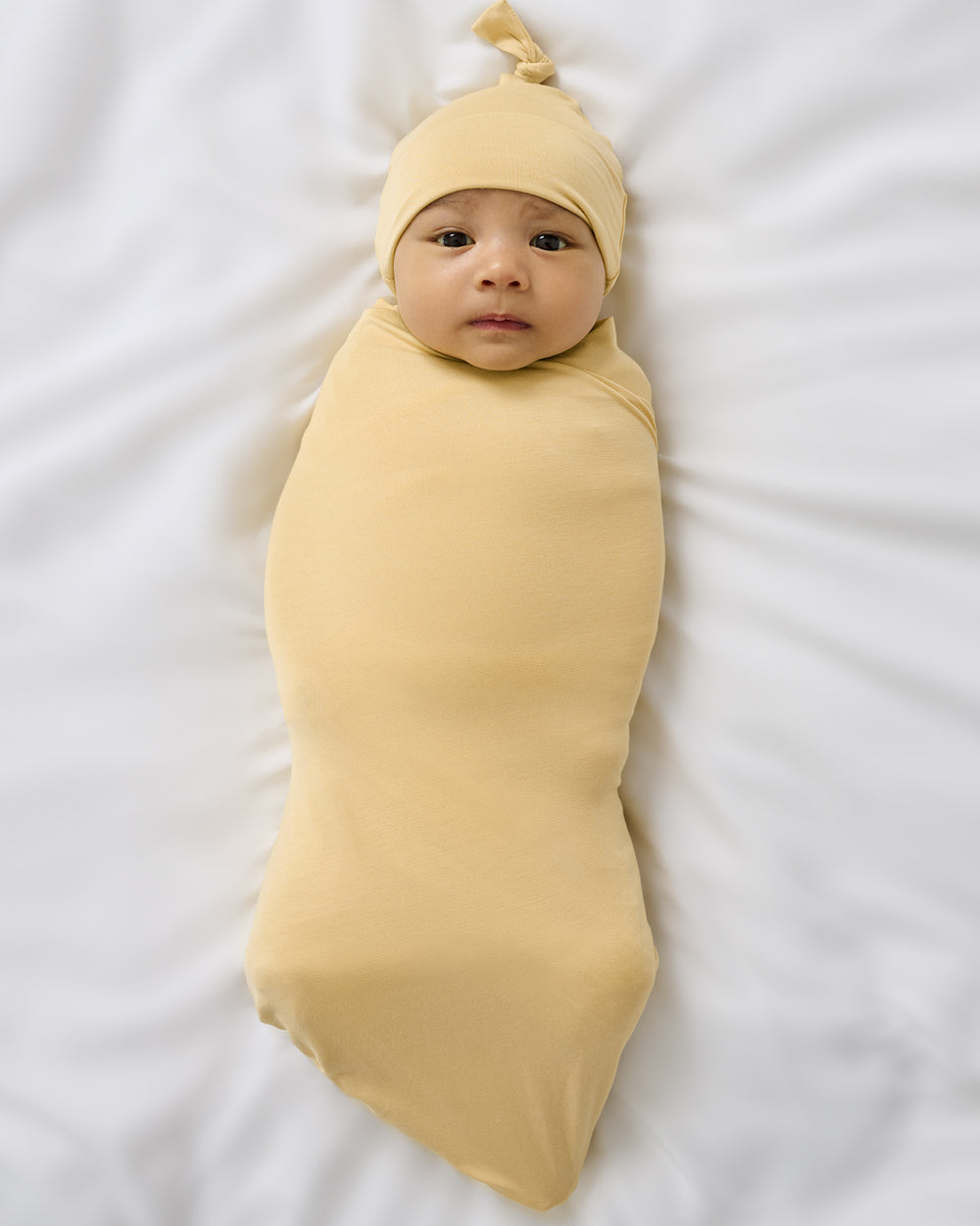 Aerial view of baby wrapped in the Sunglow Swaddle & Hat Set