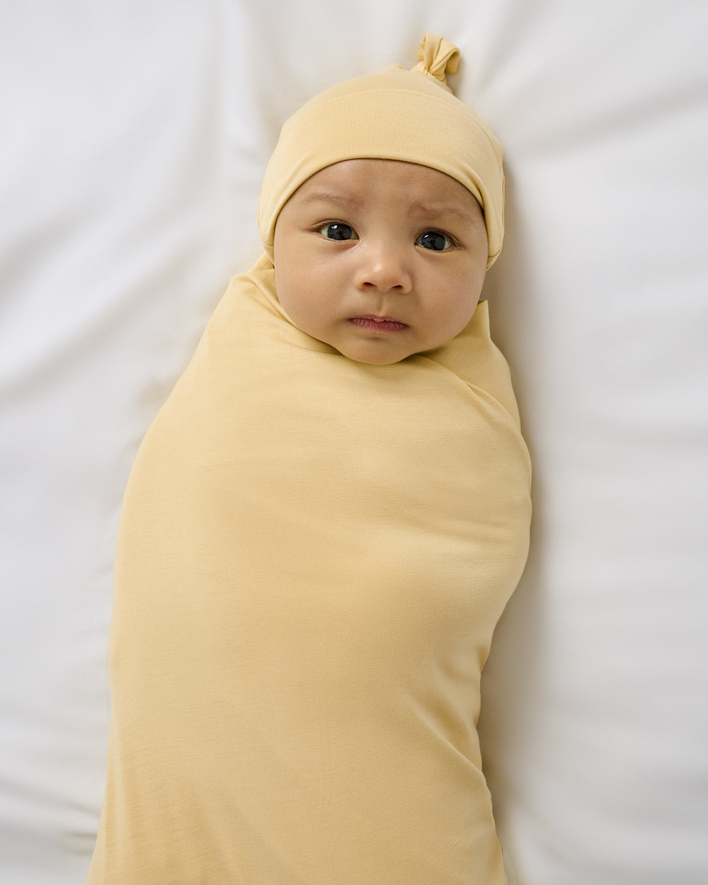Close up of newborn swaddled in the Sunglow Swaddle & Hat Set