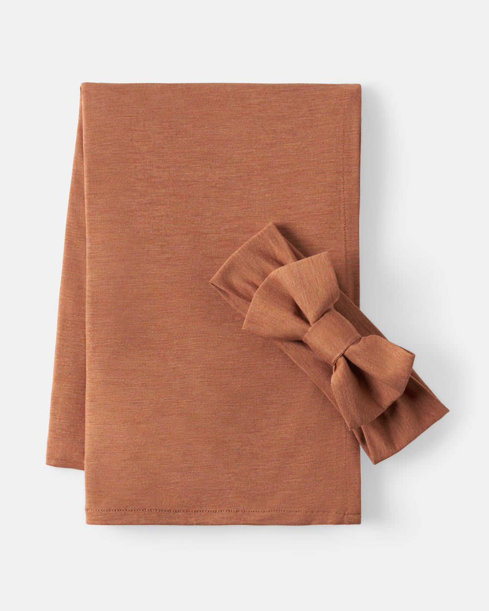 A terracotta-colored fabric napkin set, featuring a flat folded napkin and a matching ruffled bow, displayed on a clean off-white background.