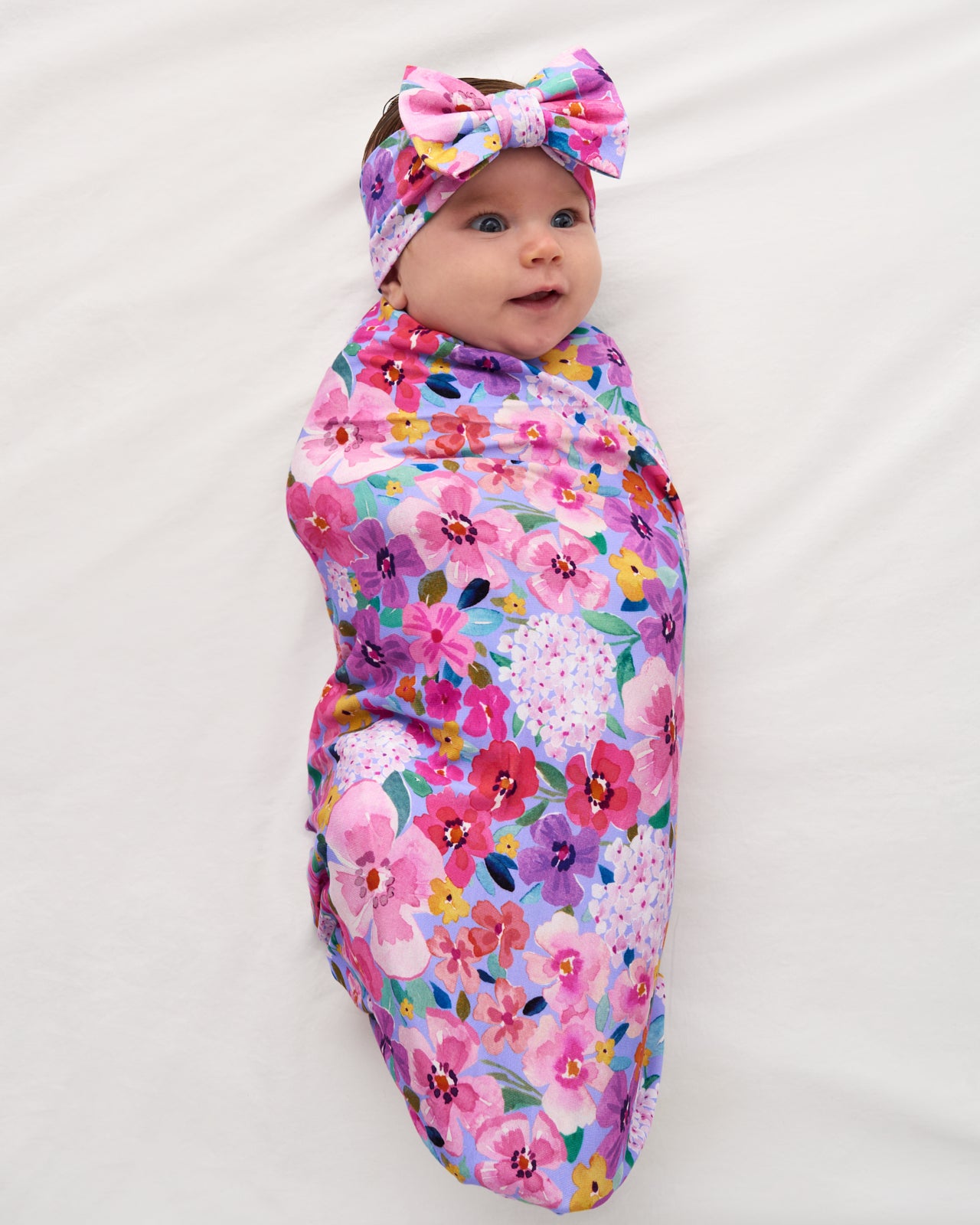 Aerial view of baby swaddled in the Sweet Sprigs Swaddle & Luxe Bow Headband Set