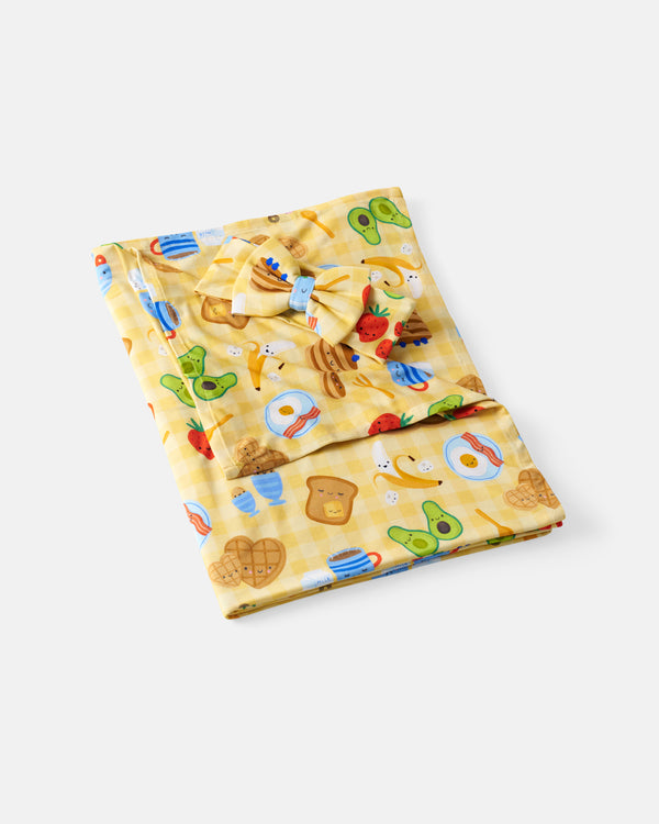 Flat lay of the Breakfast Bunch Swaddle & Luxe Bow Headband Set