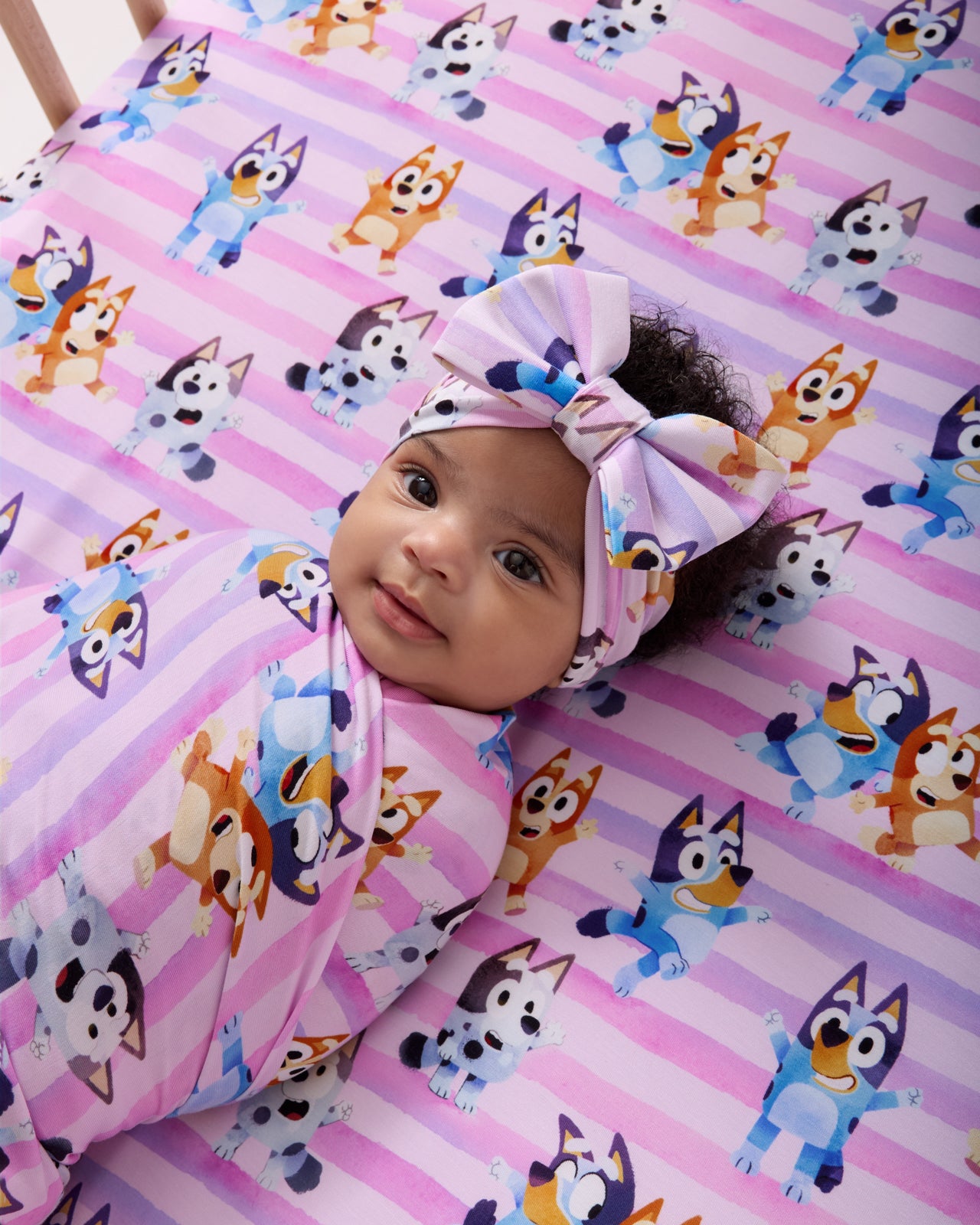 Close up of baby swaddled in the Pink Bluey Dance All Day Swaddle & Luxe Bow Headband Set