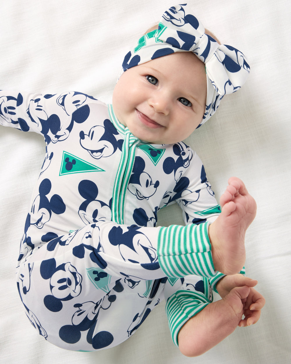 Aerial view of baby wearing the Disney Varsity Mickey Mouse Luxe Bow Headband and Zippy