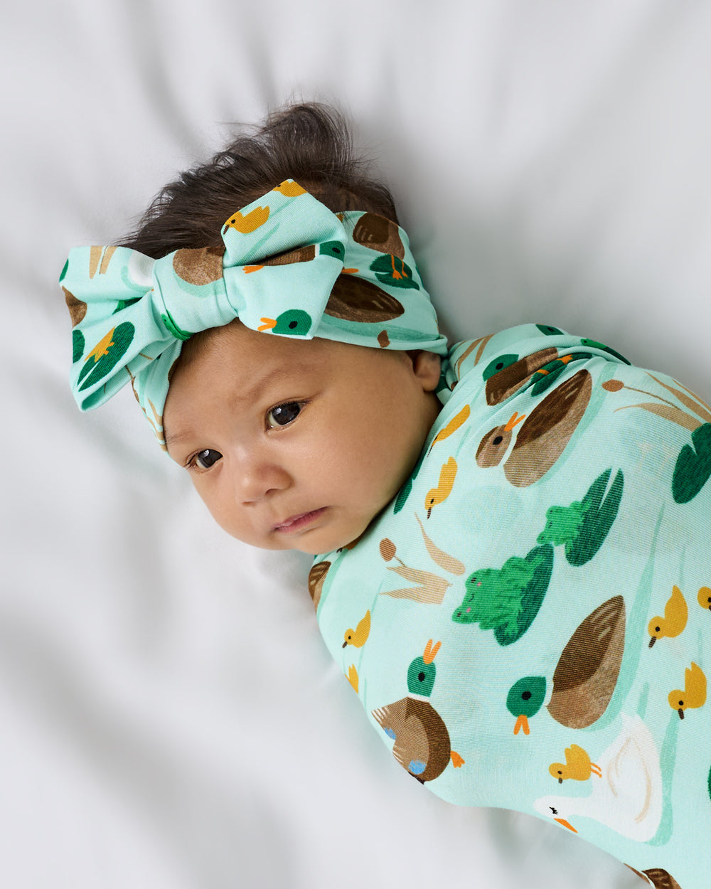 Close up of baby wearing the Puddle Jumpers Swaddle & Luxe Bow Headband Set