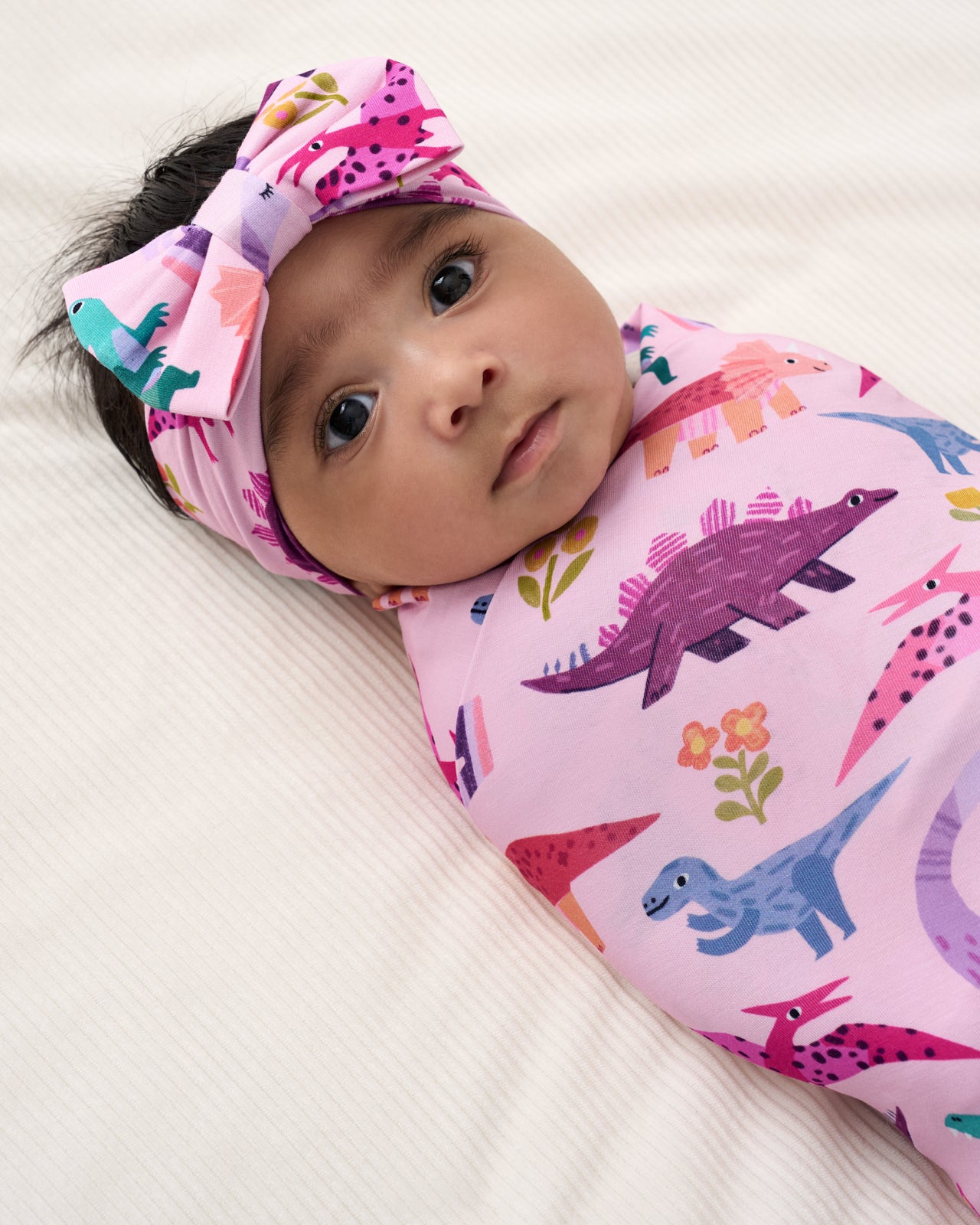 Close up of baby wearing the Pink Roar & Explore Swaddle & Luxe Bow Headband Set