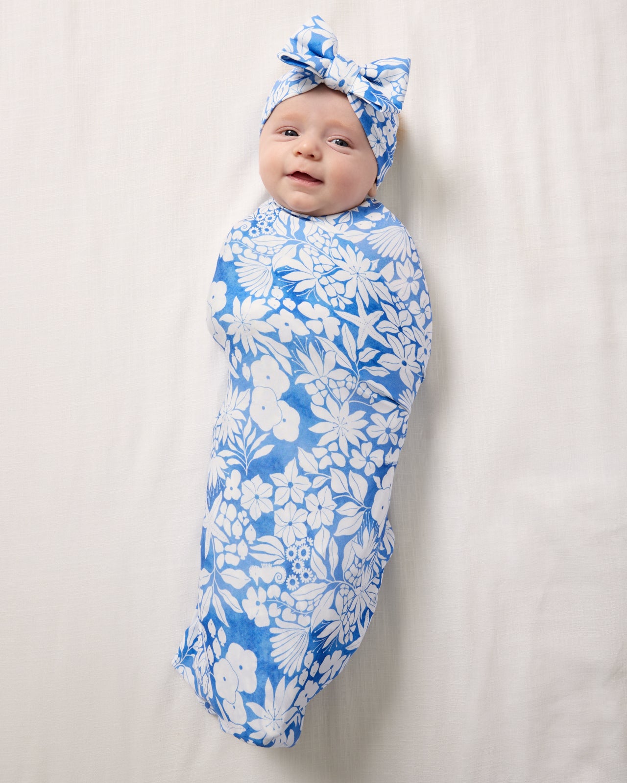 Aerial view of baby wrapped in the Azure Garden Swaddle & Luxe Bow Headband Set