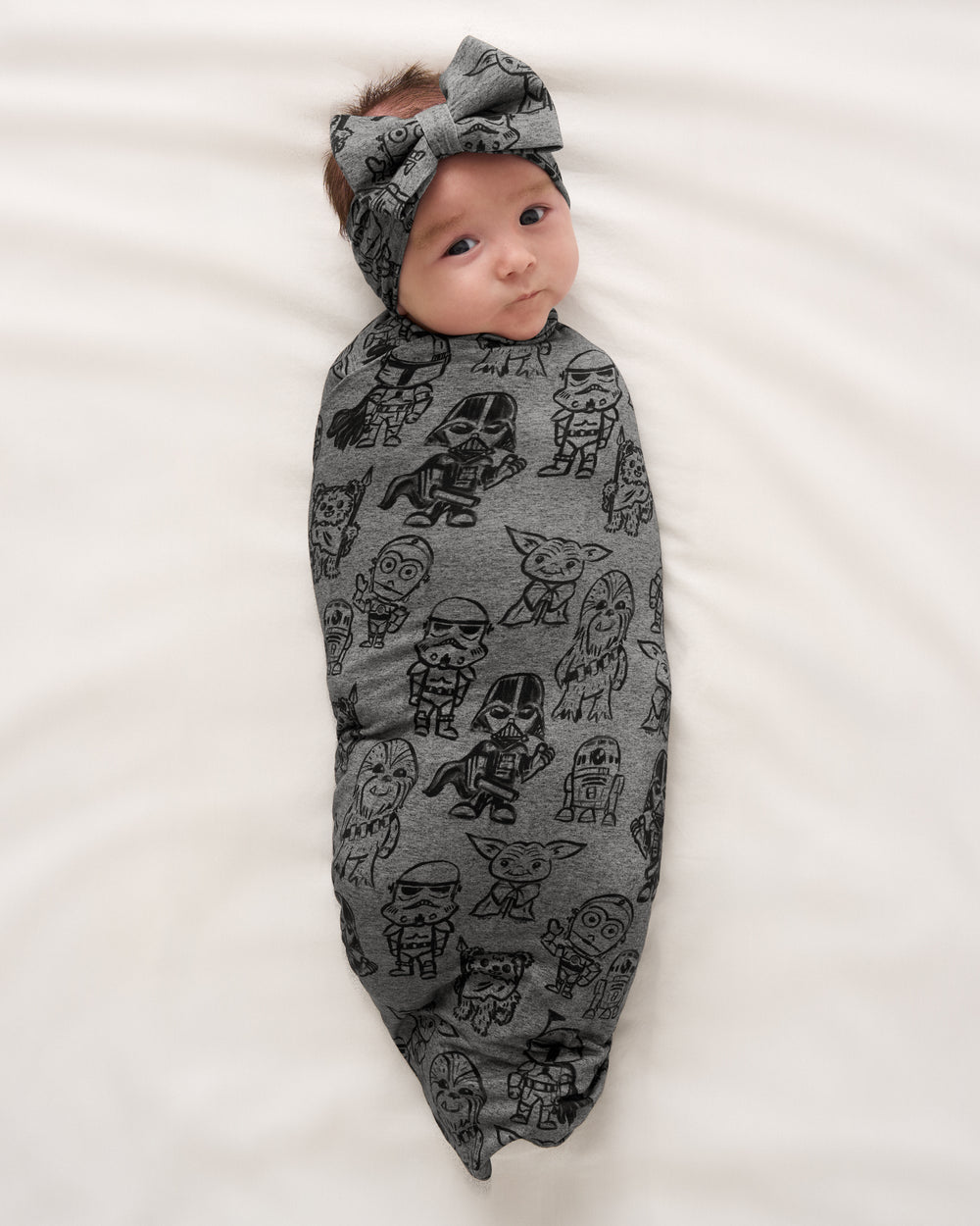 Aerial view of baby wearing the Star Wars Far, Far, Away Friends Swaddle & Luxe Bow Headband Set
