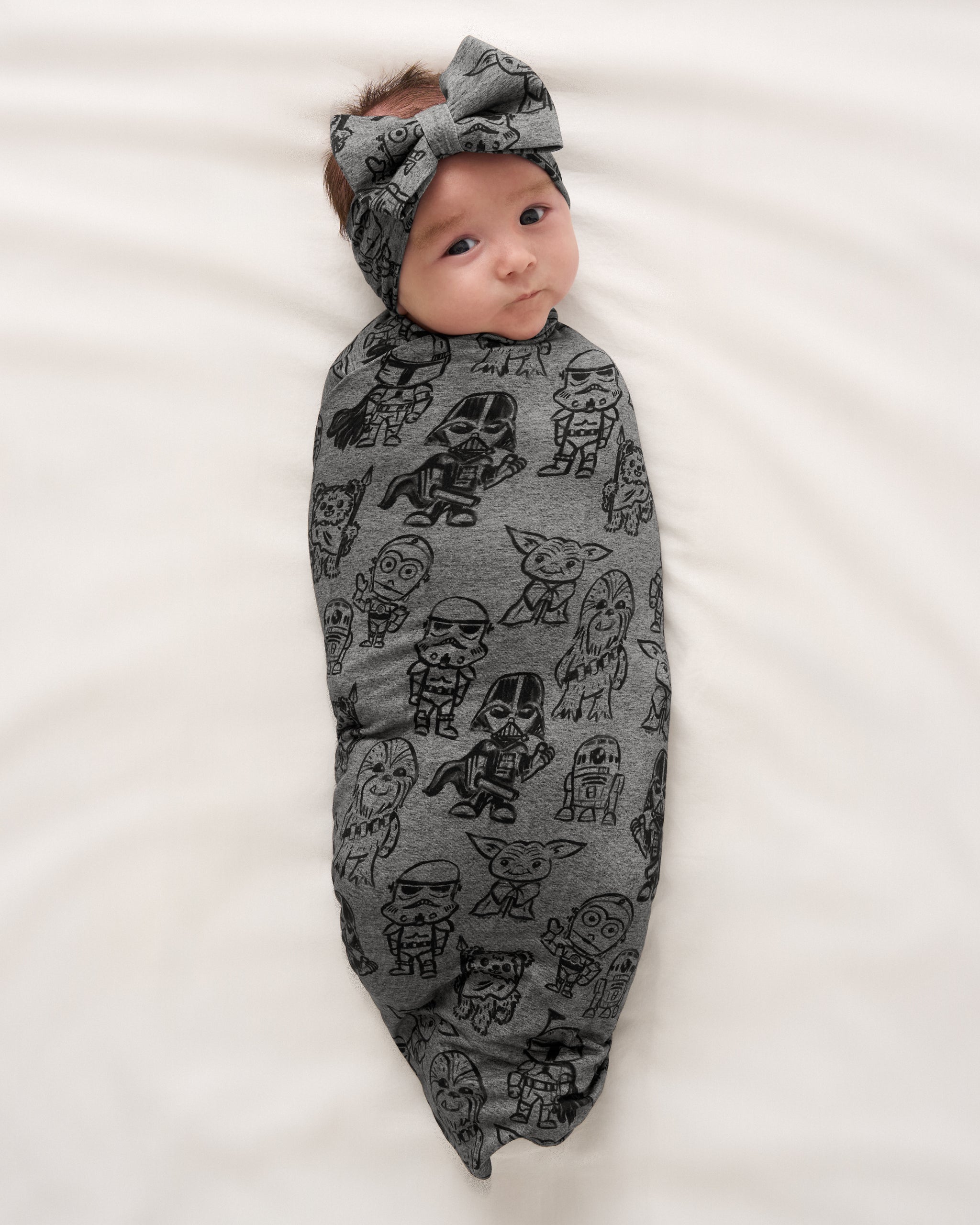 Aerial view of baby wearing the Star Wars Far, Far, Away Friends Swaddle & Luxe Bow Headband Set