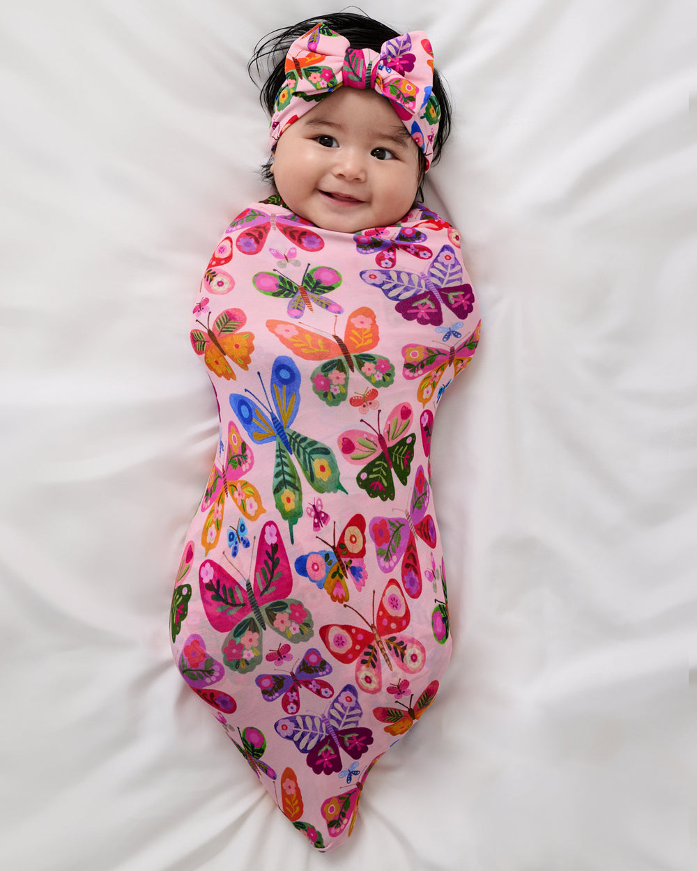 Aerial view of baby wrapped in the Flutter Garden Swaddle & Luxe Bow Headband Set