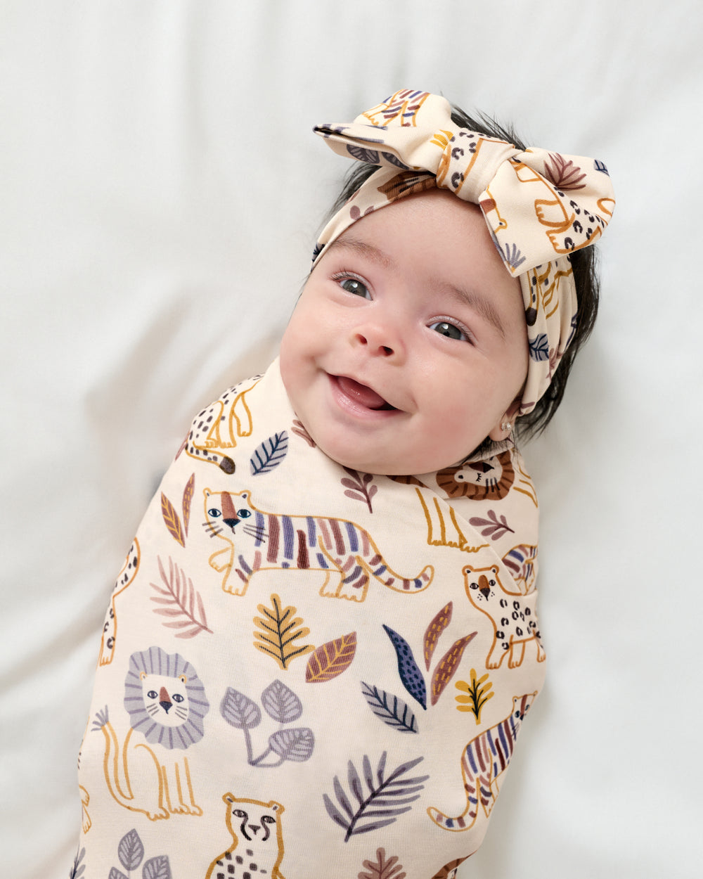 Close up of newborn wrapped in the Savanna Friends Swaddle & Luxe Bow Headband Set