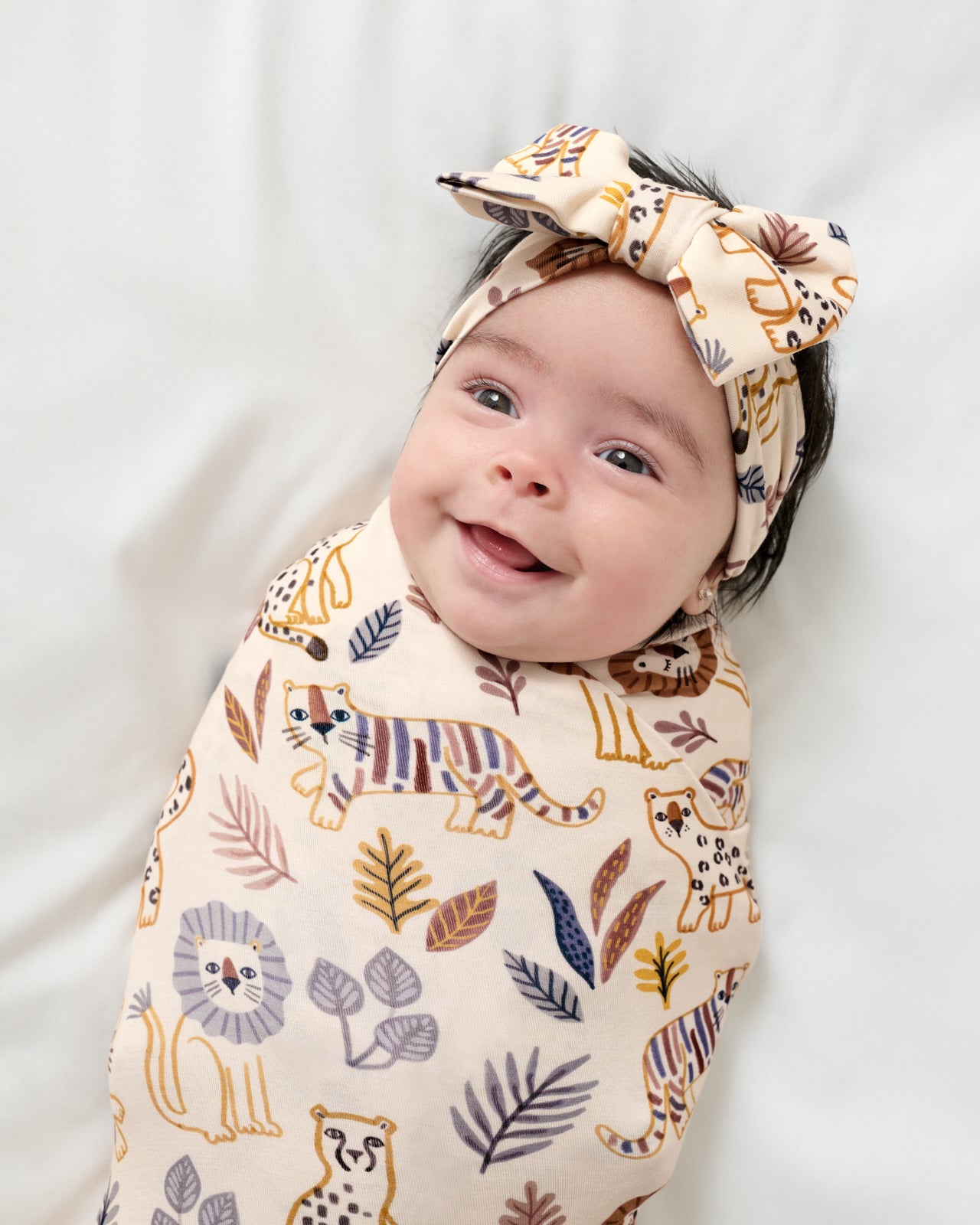 Close up of newborn wrapped in the Savanna Friends Swaddle & Luxe Bow Headband Set