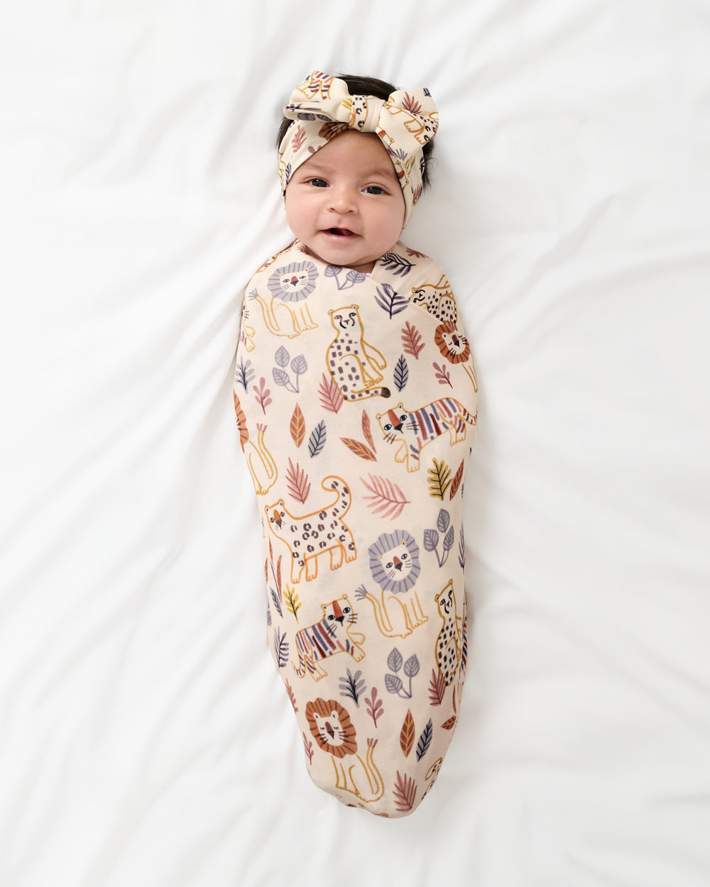 Aerial view of newborn swaddled in the Savanna Friends Swaddle & Luxe Bow Headband Set