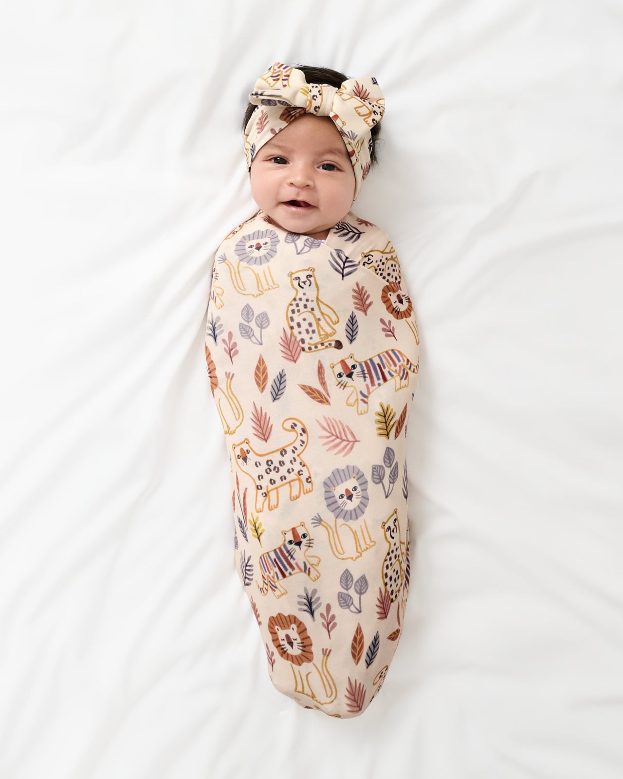 Aerial view of newborn swaddled in the Savanna Friends Swaddle & Luxe Bow Headband Set