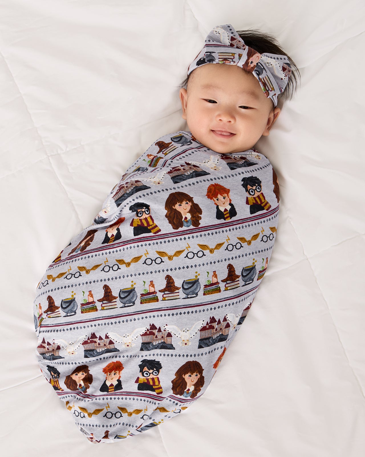 Newborn wrapped in the Harry Potter™ Spellbinding Studies Swaddle & Luxe Bow Headband Set