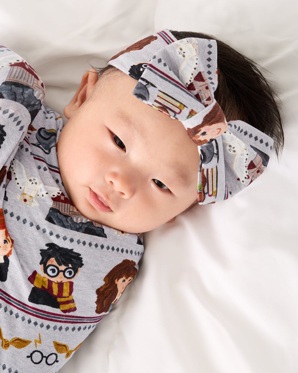 Close up of baby swaddled in the Harry Potter™ Spellbinding Studies Swaddle & Luxe Bow Headband Set