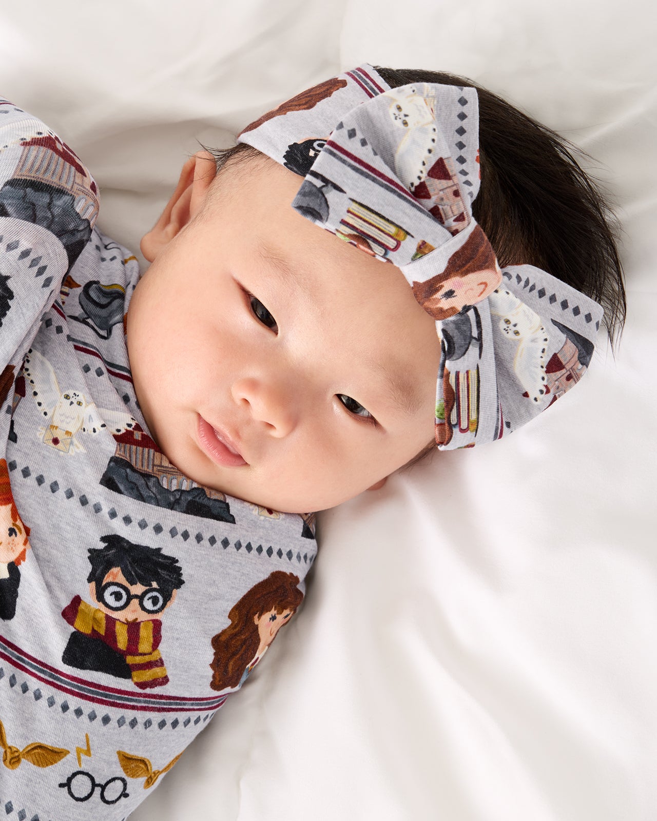 Close up of baby swaddled in the Harry Potter™ Spellbinding Studies Swaddle & Luxe Bow Headband Set