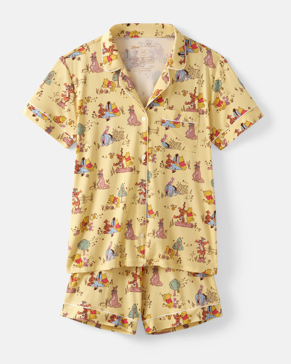 A two-piece short-sleeve pajama set featuring a light yellow button-up shirt and matching shorts, both decorated with a colorful cartoon print of characters in various poses. The pajamas are displayed flat against a light gray background.
