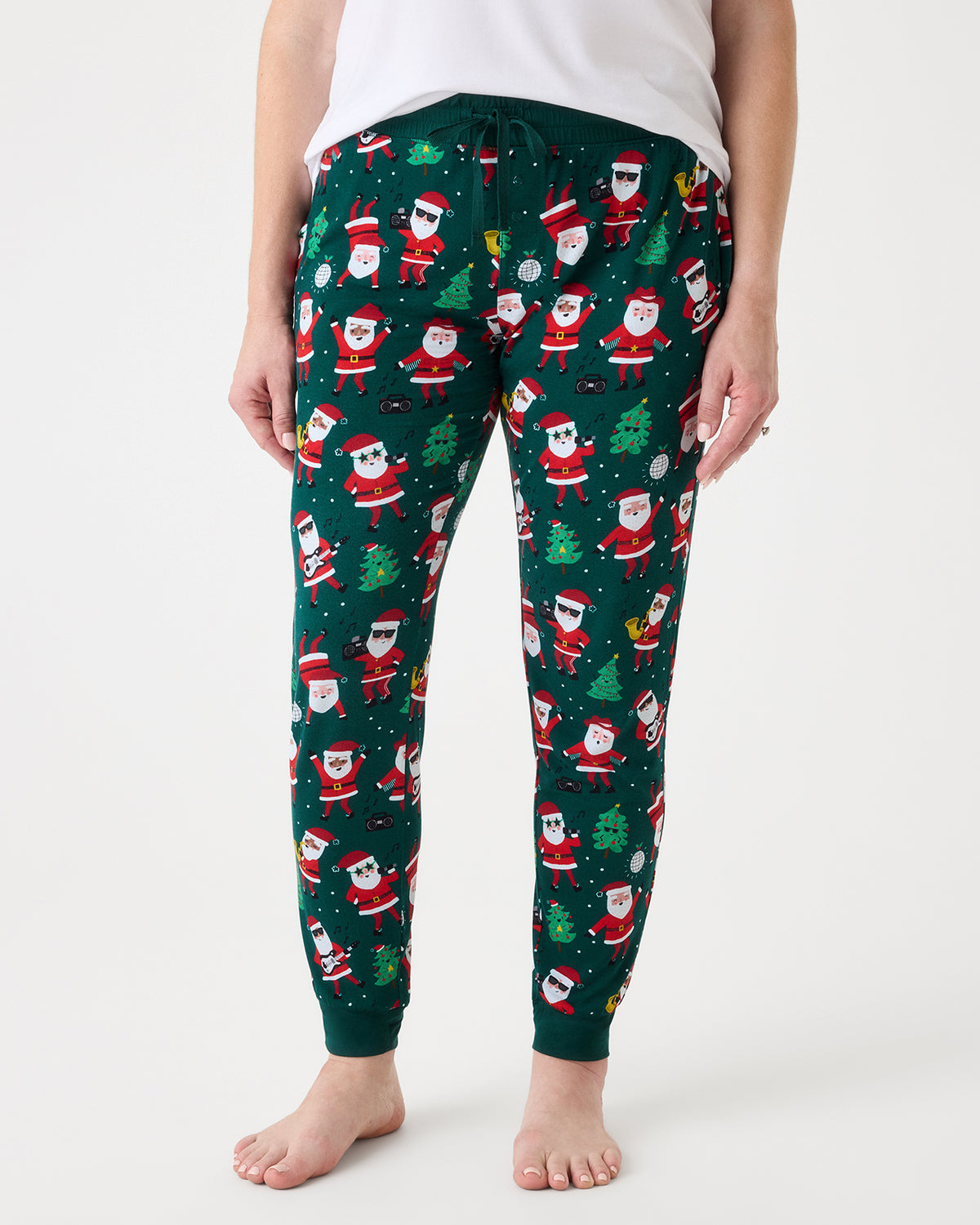 A person wearing dark green jogger-style pants with an all-over Christmas Santa Claus print, shown from the waist down against a plain light background.