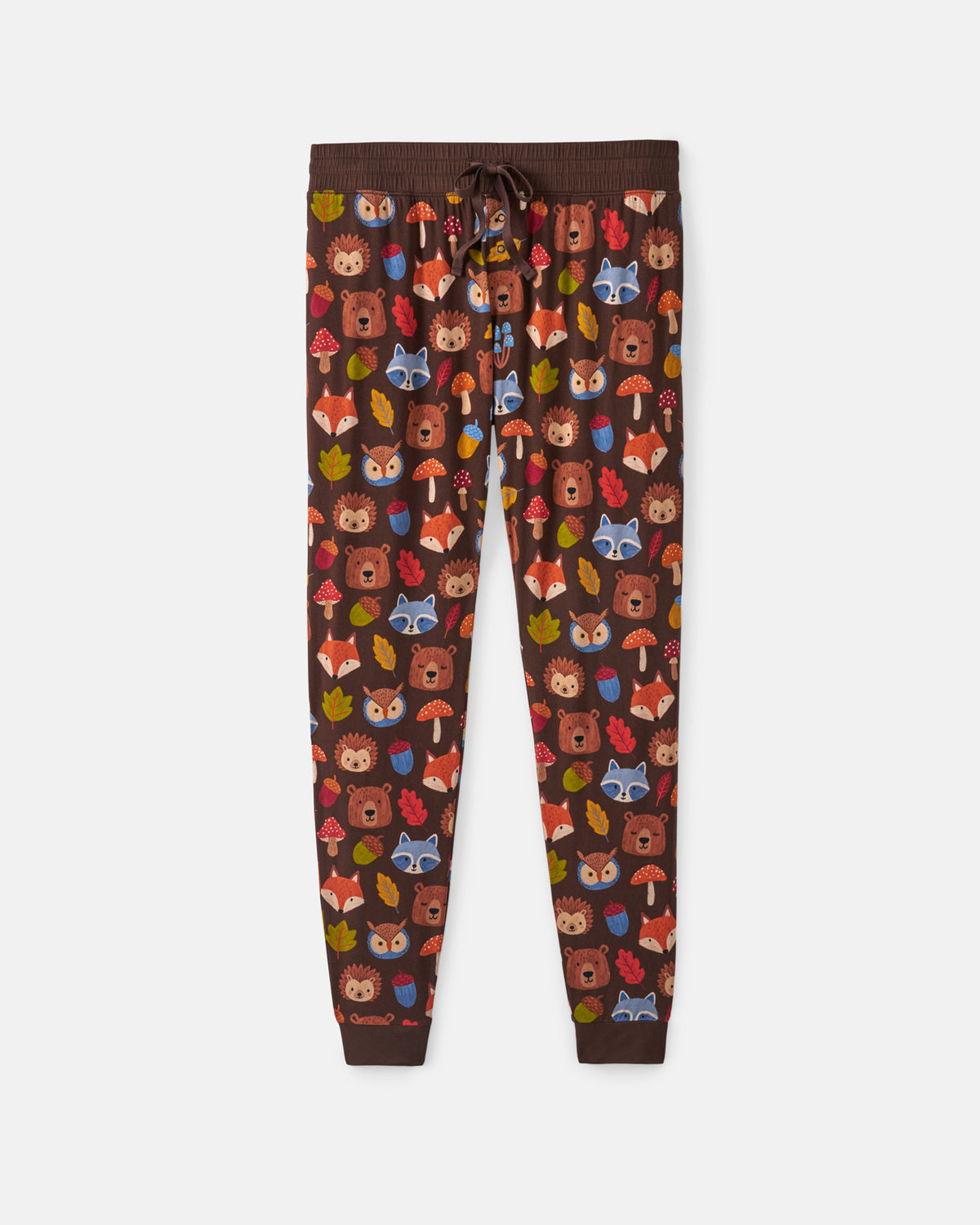 A pair of dark brown jogger pants featuring an all-over woodland animal print with foxes, owls, mushrooms, and leaves in autumn colors, shown flat against a light gray background.