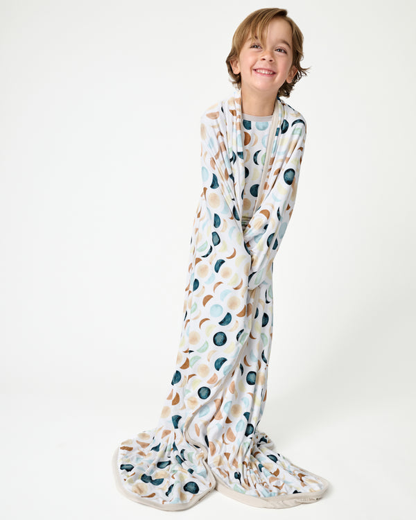 Standing boy wrapped in the Luna Neutral Large Cloud Blanket®