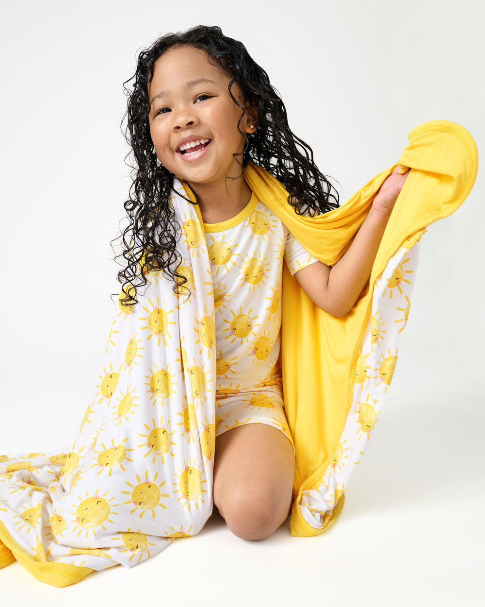Sitting girl wrapped in the Sunshine Large Cloud Blanket®