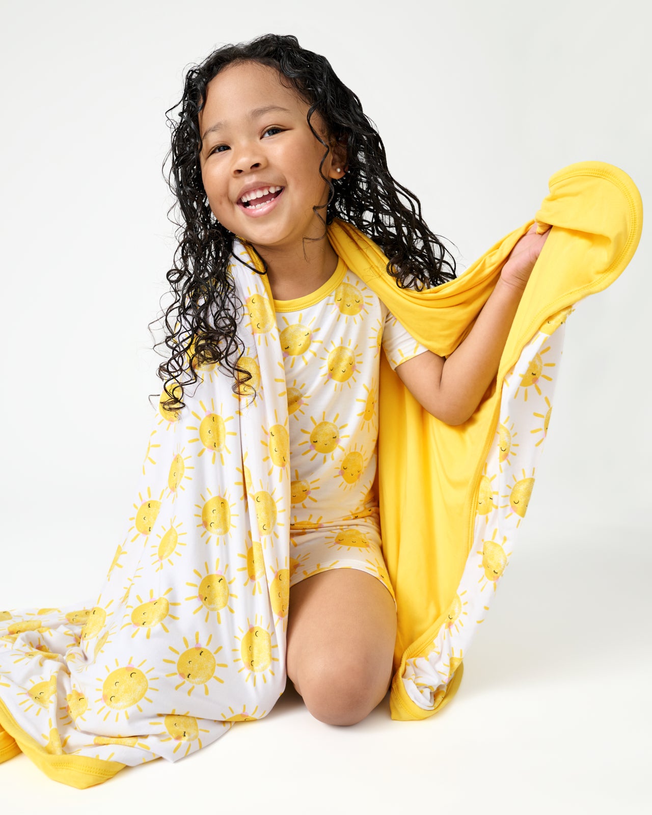 Sitting girl wrapped in the Sunshine Large Cloud Blanket®