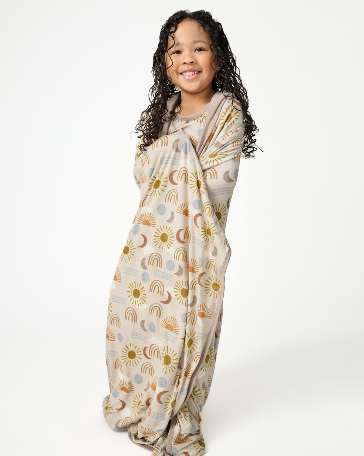 Standing child wrapped in the Desert Sunrise Large Cloud Blanket®
