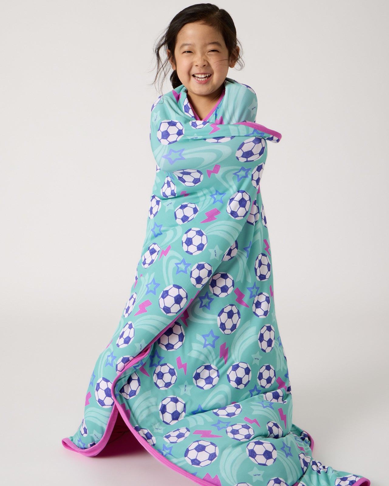 Standing girl wrapped in the Aqua Soccer Stars Large Cloud Blanket®
