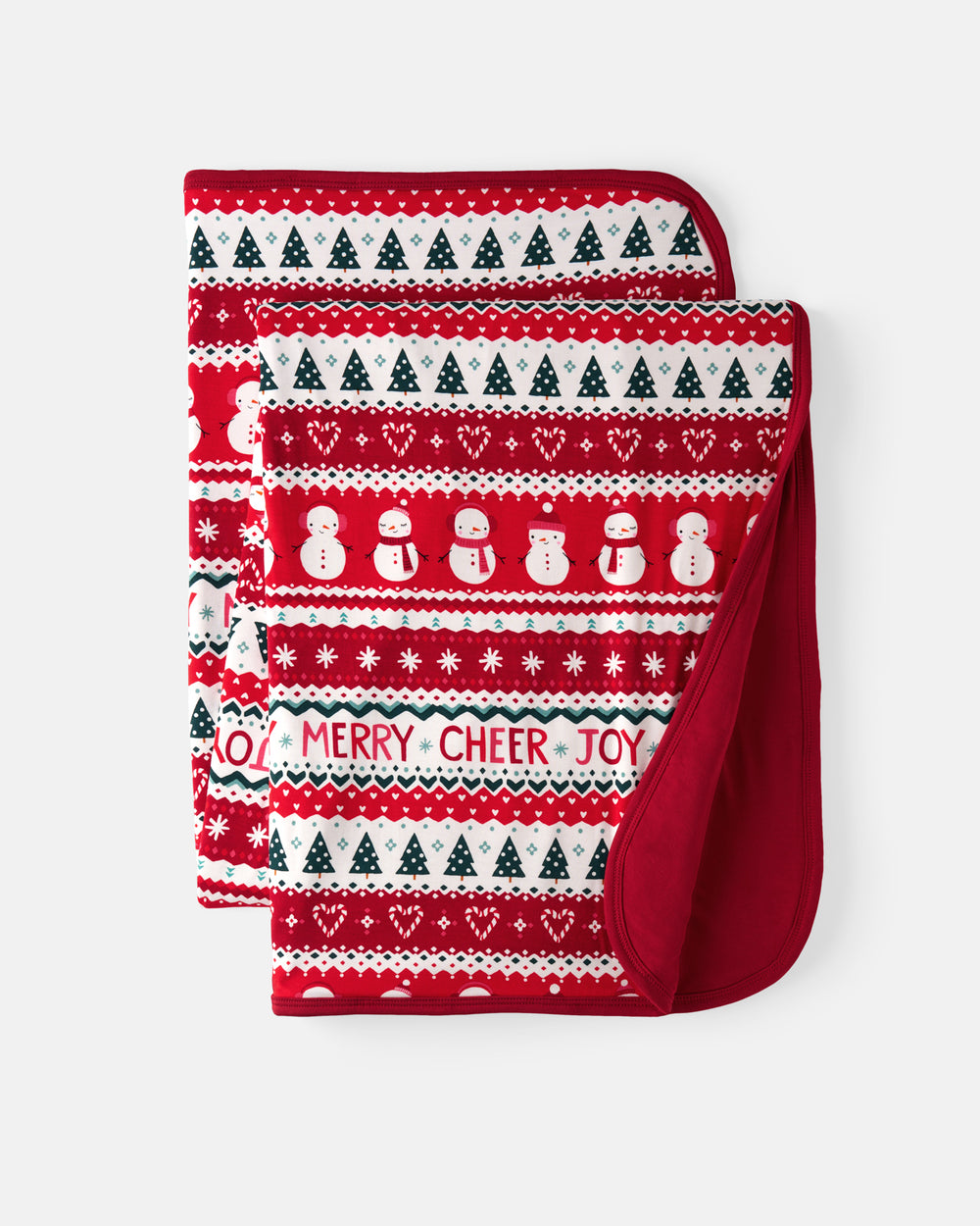 A folded Christmas blanket with a festive red and white knit pattern featuring snowmen, trees, hearts, and the text 'MERRY CHEER JOY', shown on a light gray background.