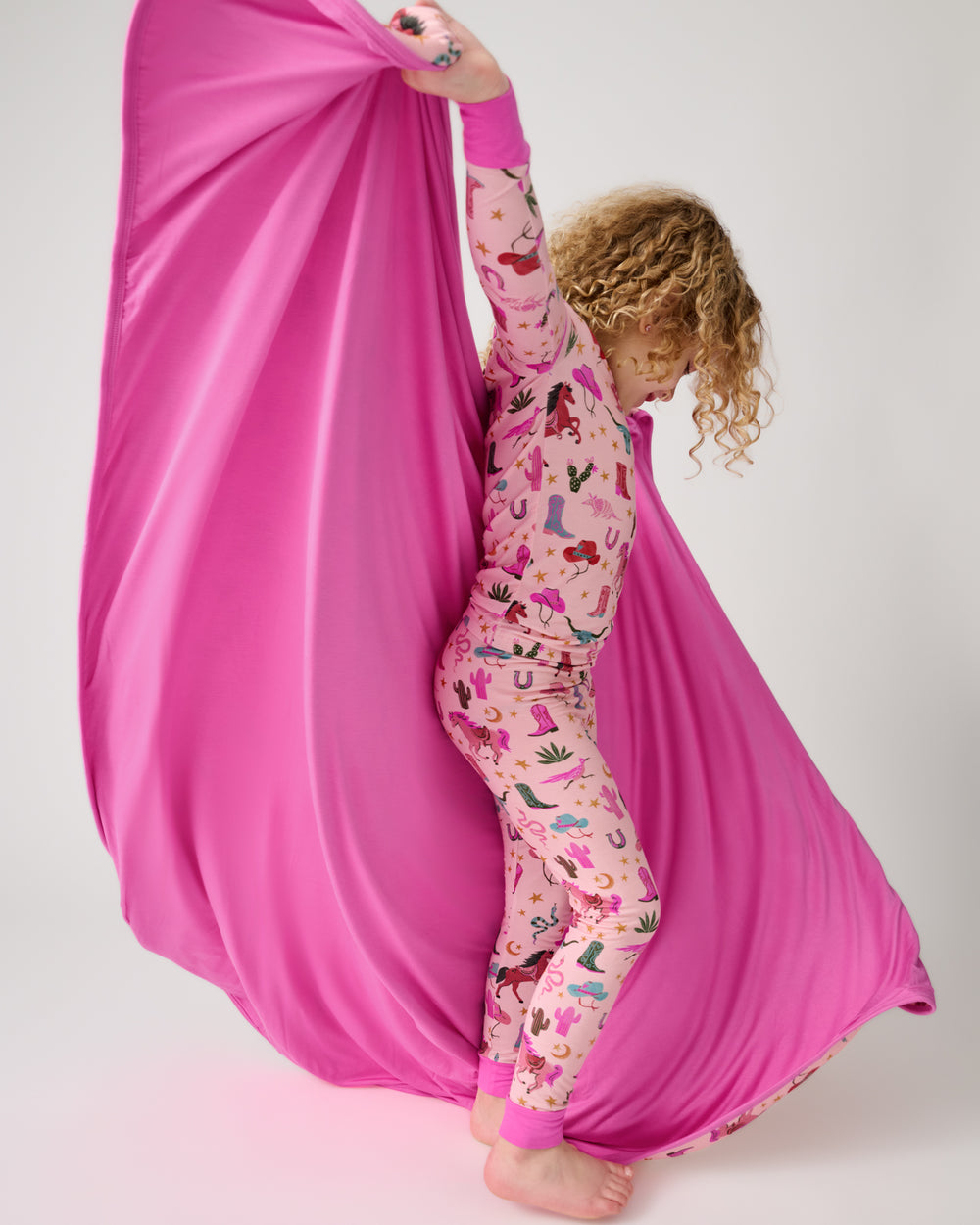 Girl holding up the Pink Rancher Roundup Large Cloud Blanket® showing the solid pink side
