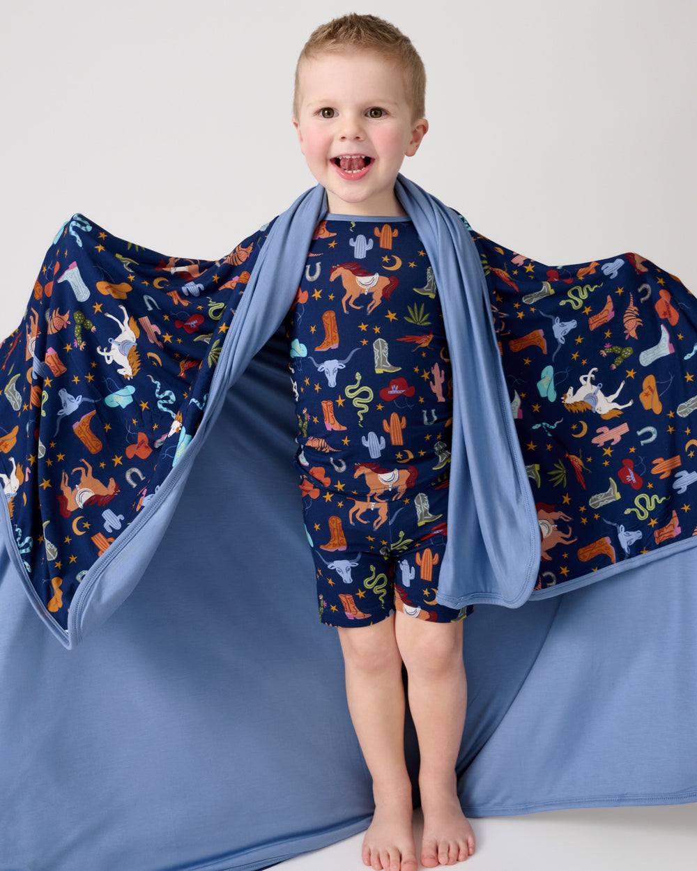 Boy holding out the Blue Rancher Roundup Large Cloud Blanket® showing the solid blue side