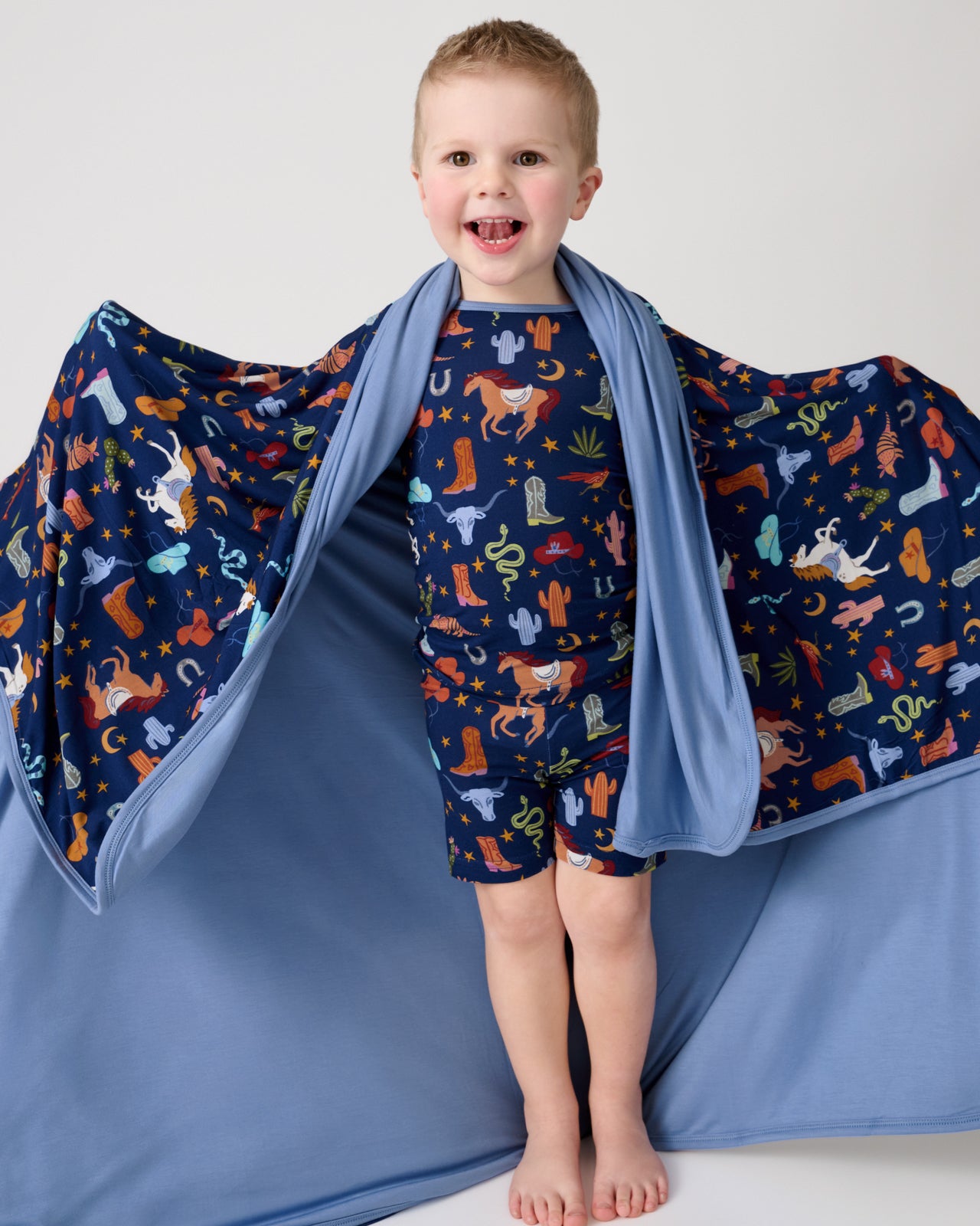 Boy holding out the Blue Rancher Roundup Large Cloud Blanket® showing the solid blue side