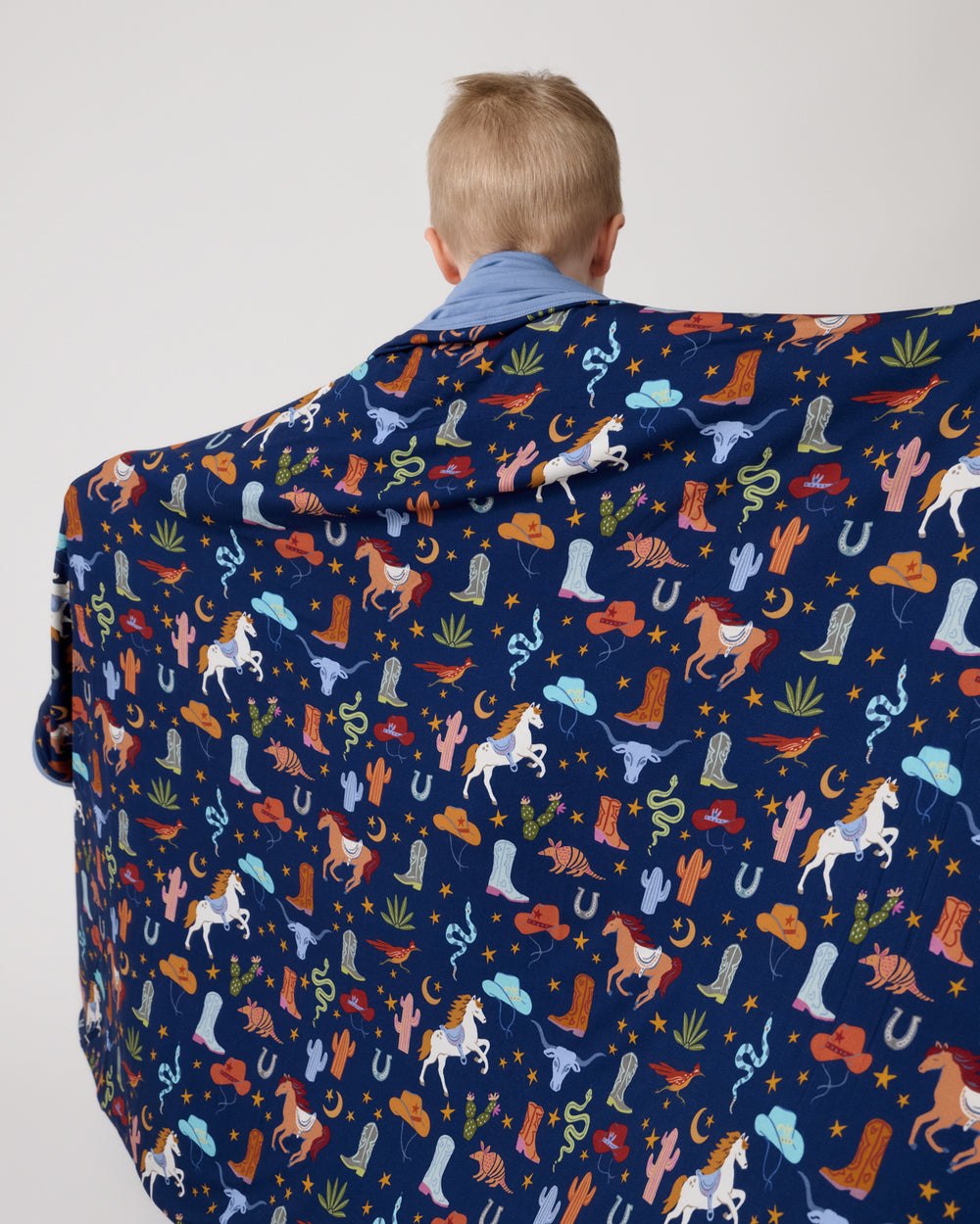 Back view of boy wrapped in the Blue Rancher Roundup Large Cloud Blanket®