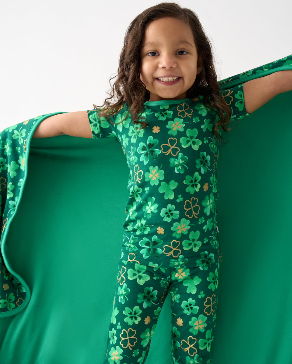 Close up of girl holding up the Clover Cuties Large Cloud Blanket® showing the solid green side