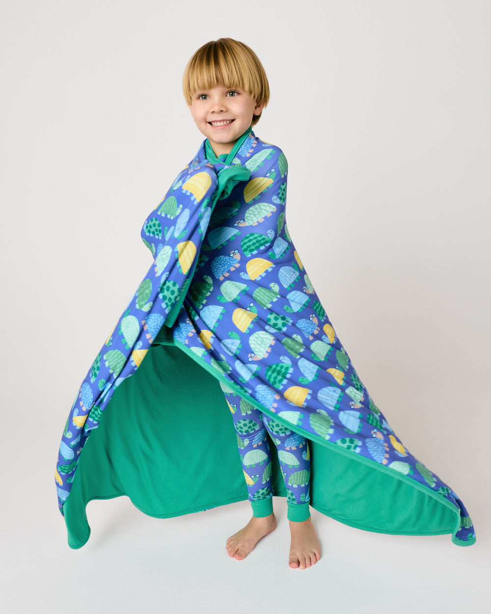 Standing child wrapped in the Shell Parade Large Cloud Blanket®
