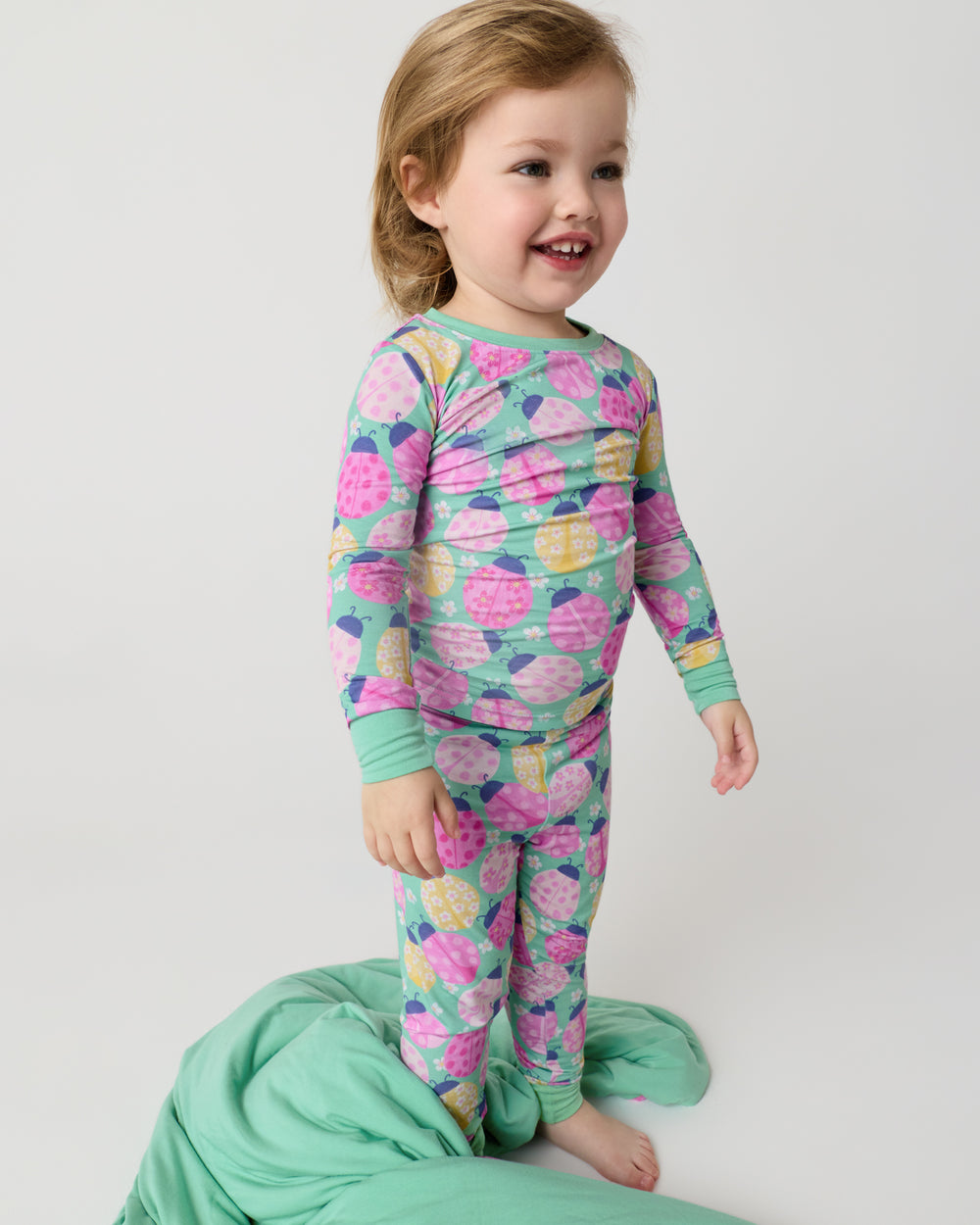 Standing child with the Ladybug Meadow Large Cloud Blanket® at her feet