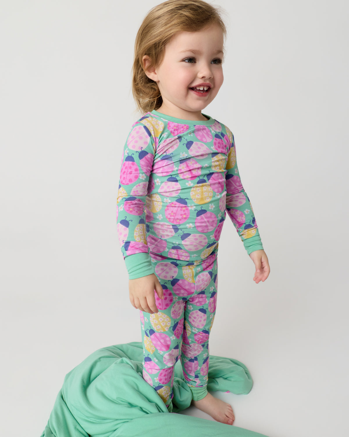 Standing child with the Ladybug Meadow Large Cloud Blanket® at her feet
