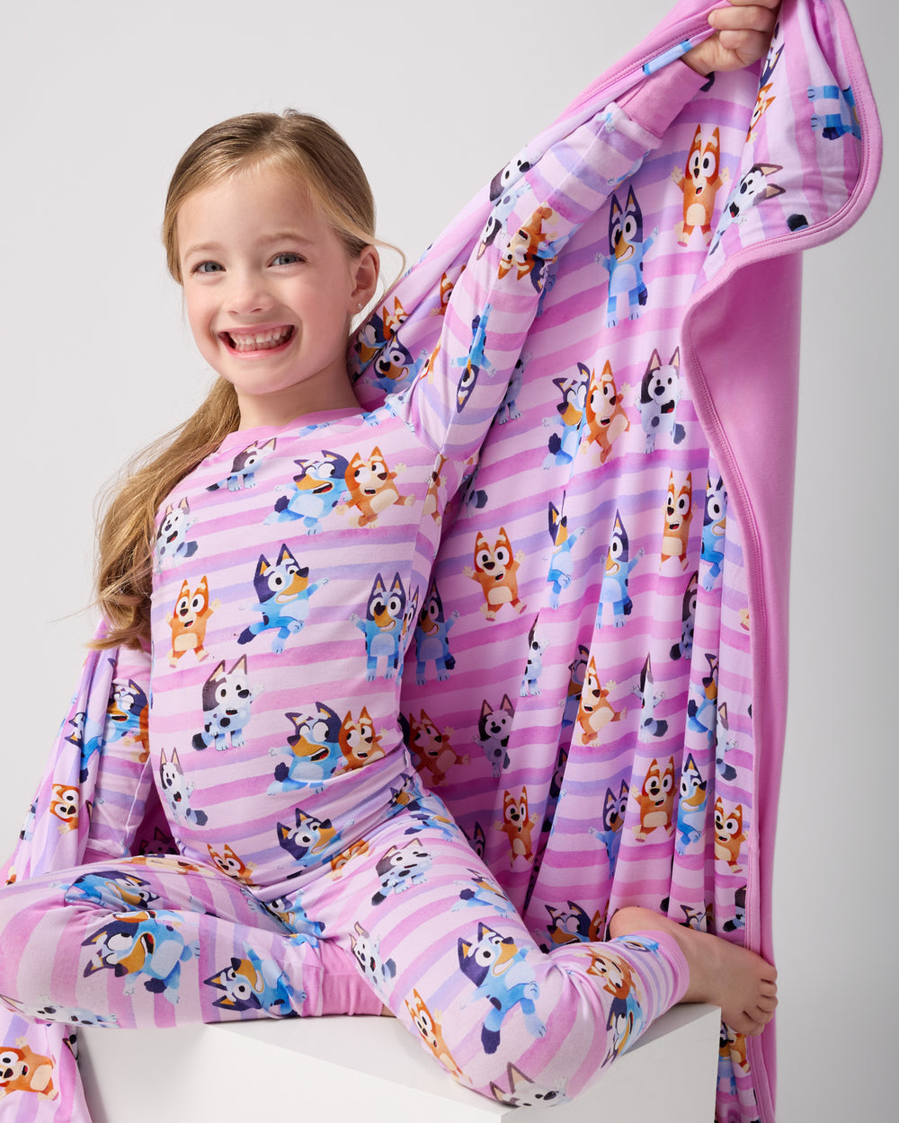 Sitting girl holding up the Pink Bluey Dance All Day Large Cloud Blanket®